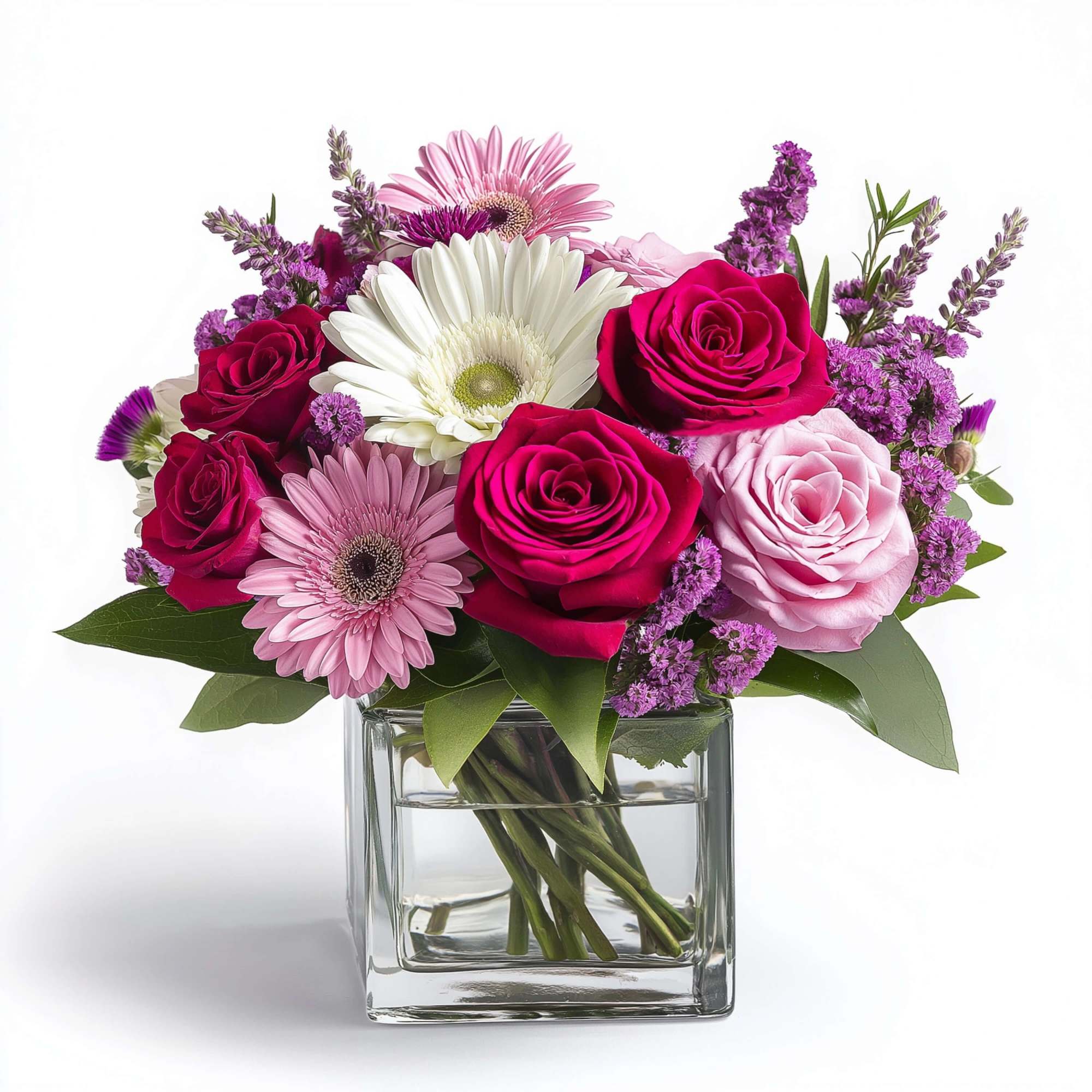 Compact arrangement of pink roses, gerbera daisies, and purple flowers in a square glass vase