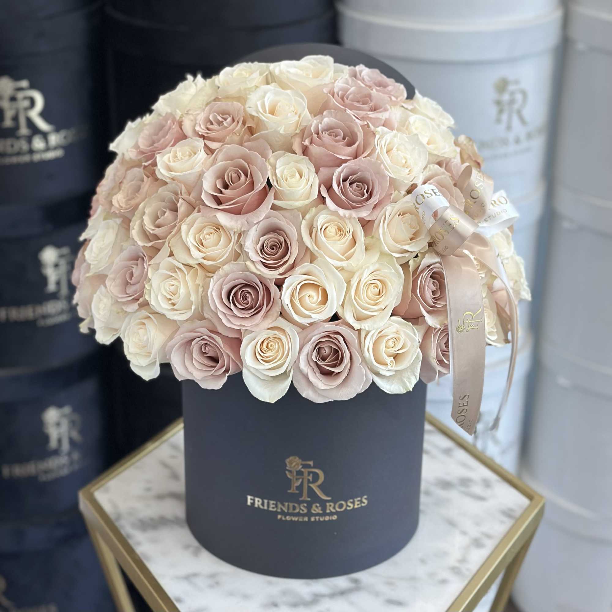 Round bouquet of blush and ivory roses in a black hat box