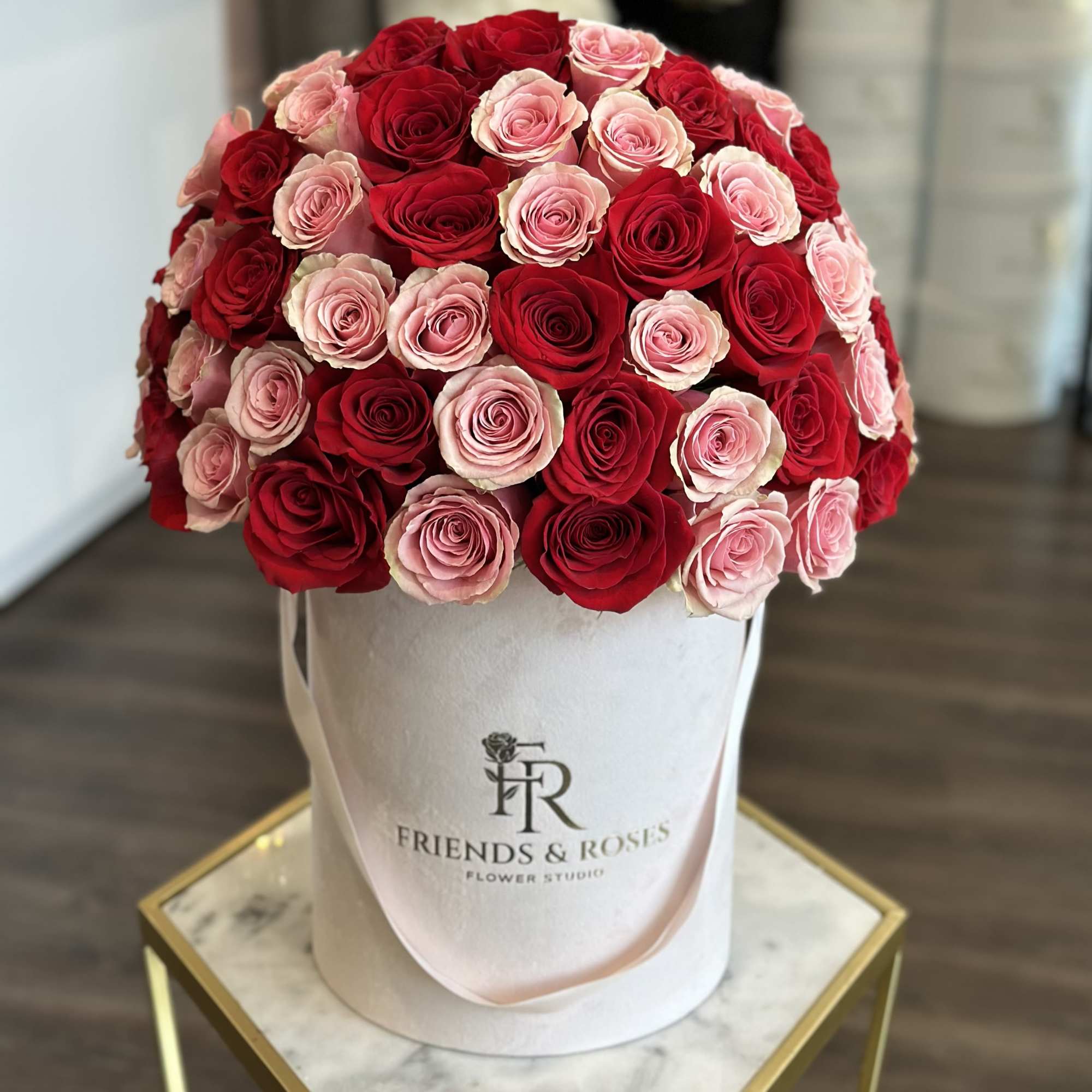 Round bouquet of red and pink roses in a white hatbox