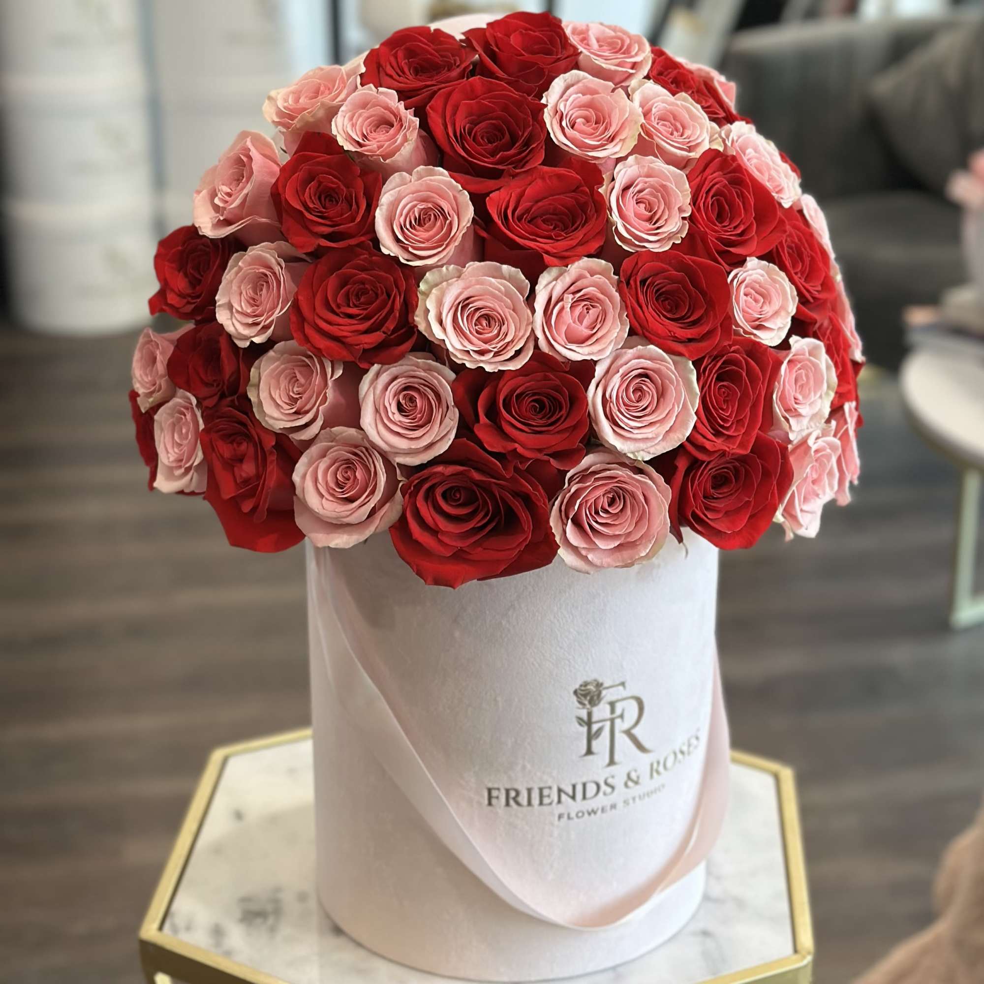 Round bouquet of red and pink roses in a white hatbox