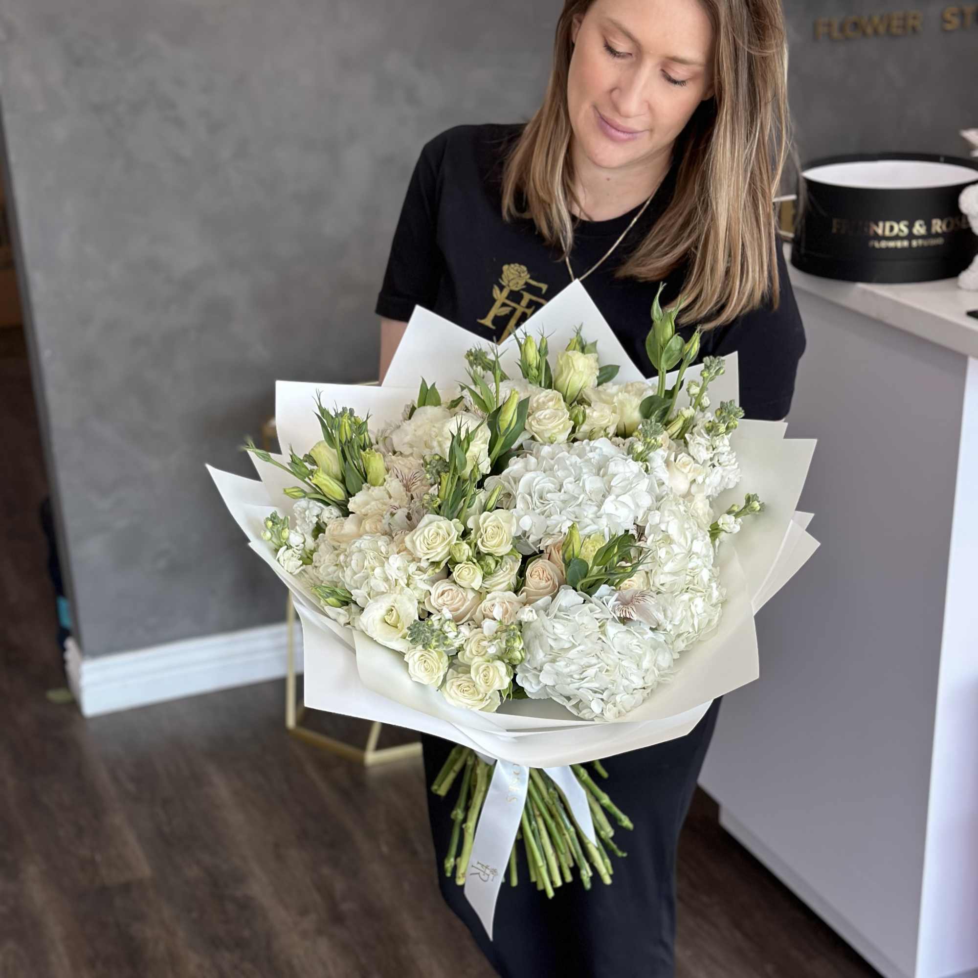 Large white bouquet with roses, hydrangeas, and green buds wrapped in white paper