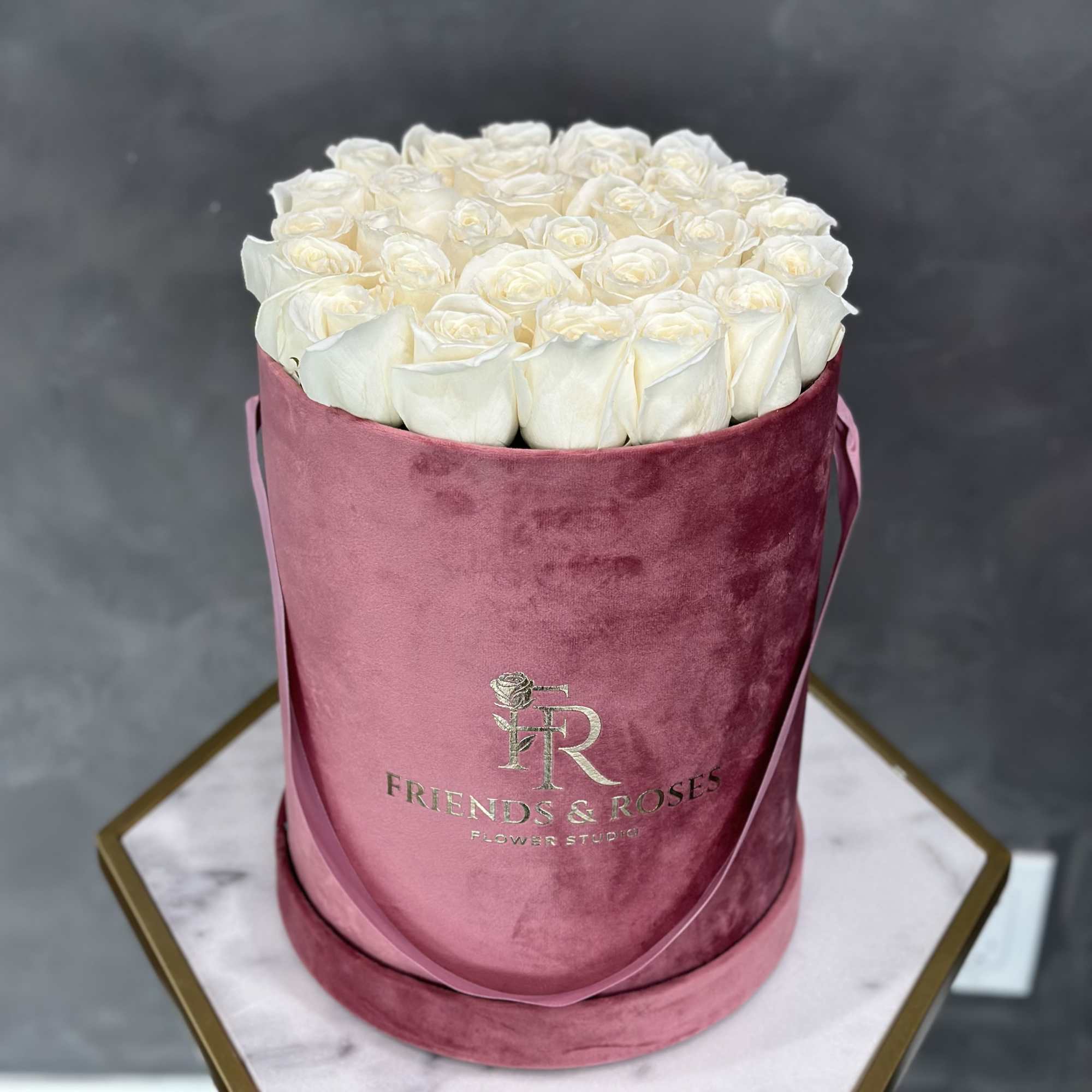 White roses arranged in a pink velvet hat box