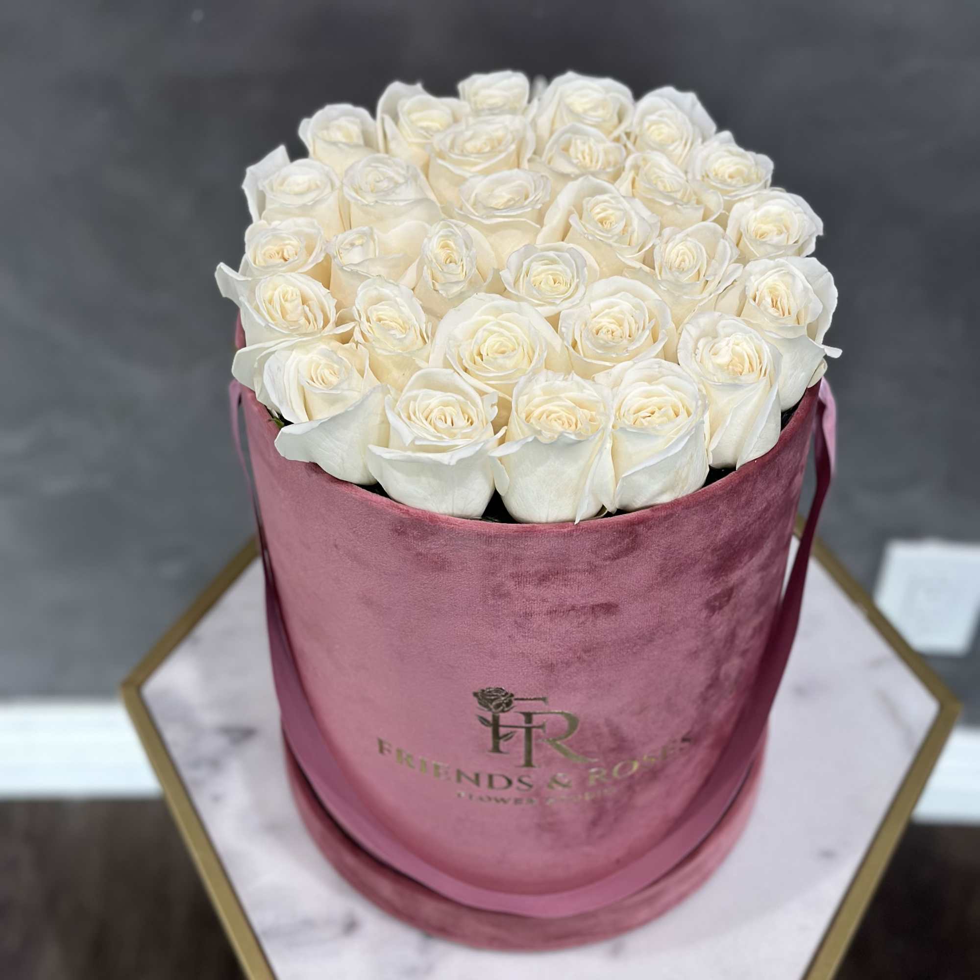 White roses arranged in a pink velvet hat box