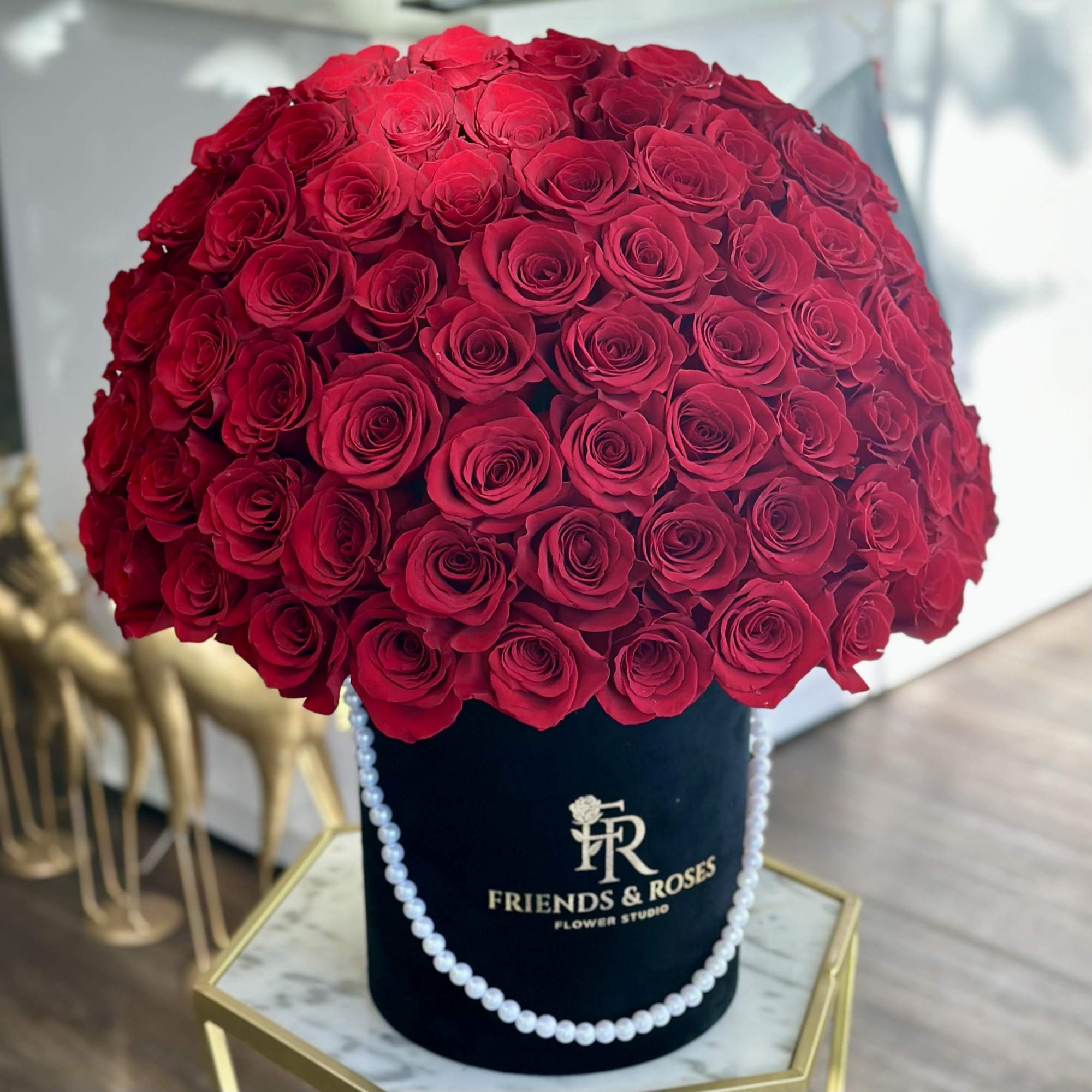 Large dome of red roses in a black hat box with pearl trim