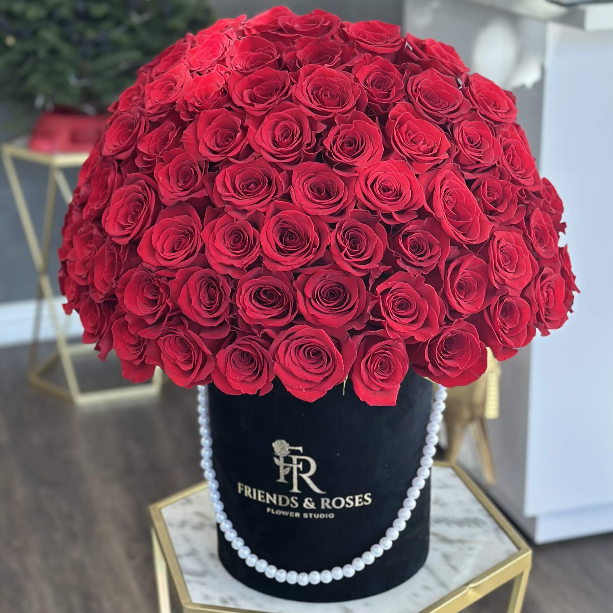 Large red rose arrangement in a black hatbox with pearl trim