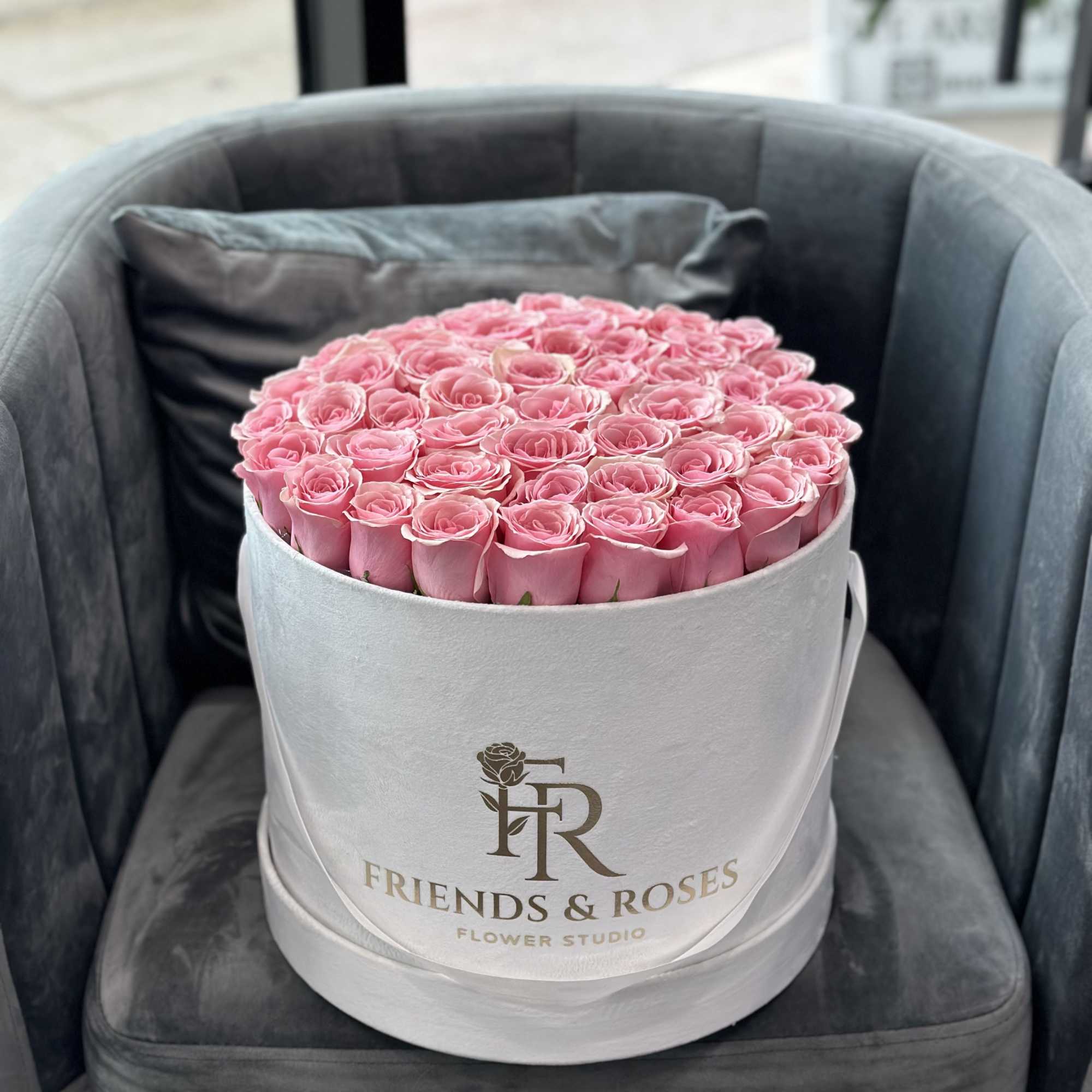 Round box of pink roses on a chair