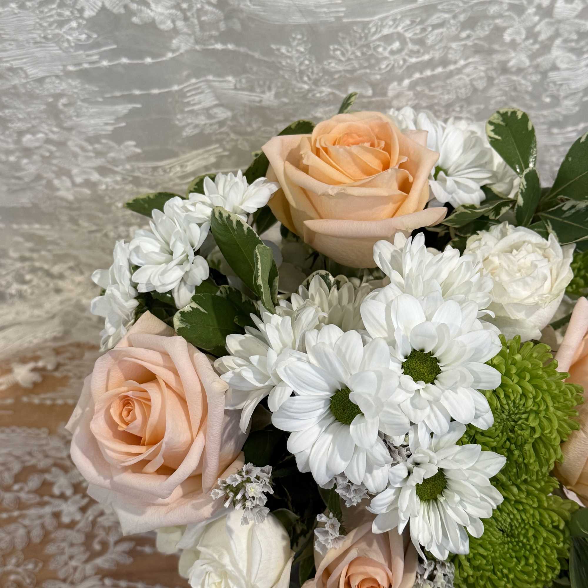 Short arrangement
Peach roses, mums, and baby white roses in a green mosaic