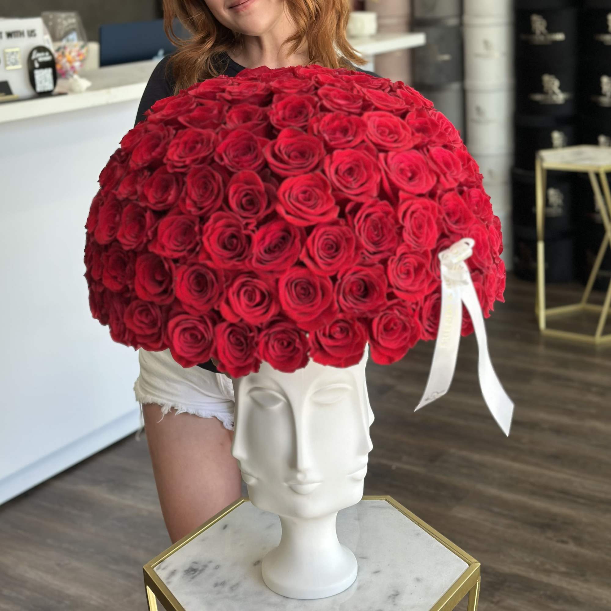 Large dome of red roses in a white sculptural vase with ribbon