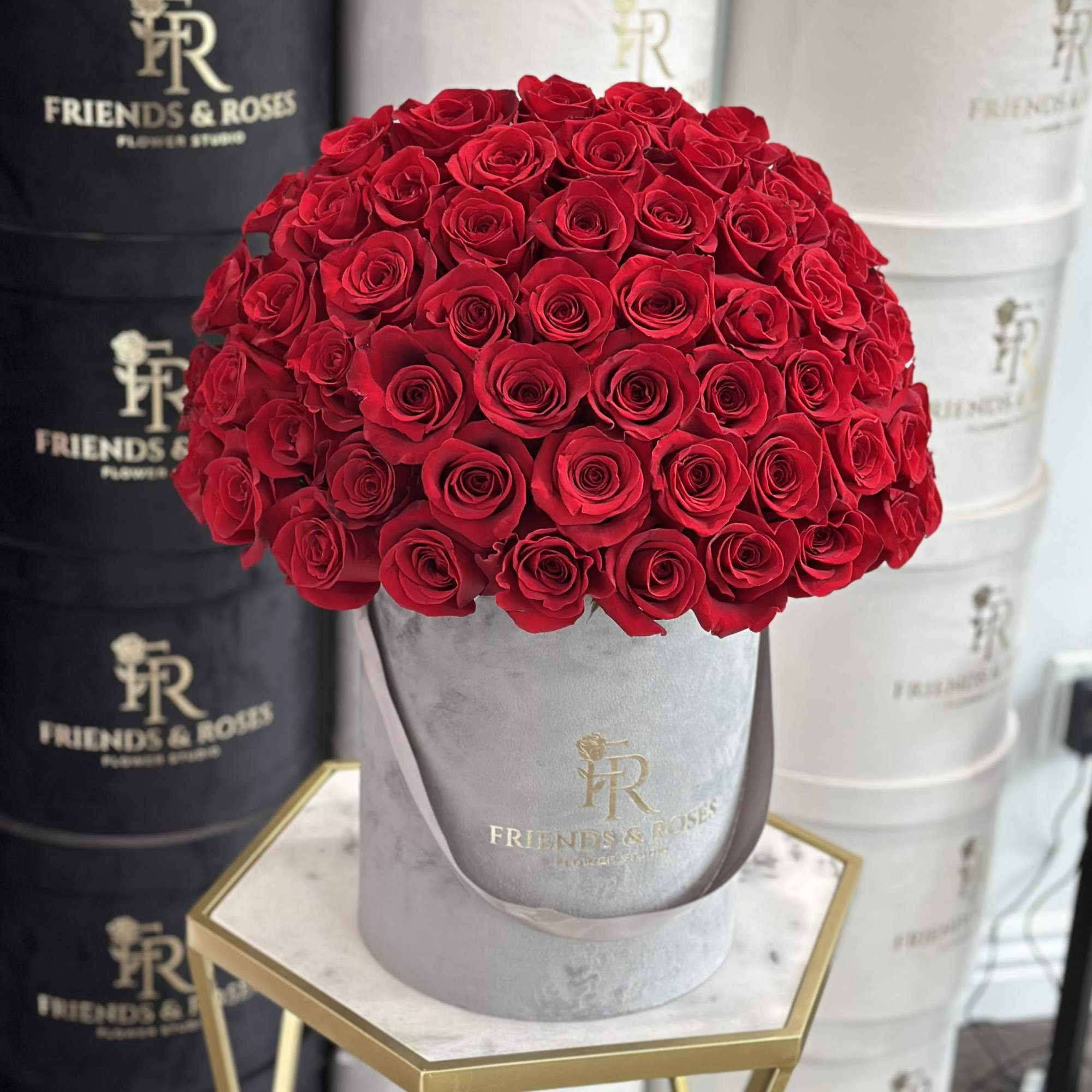 Red roses arranged in a gray hatbox with a ribbon handle