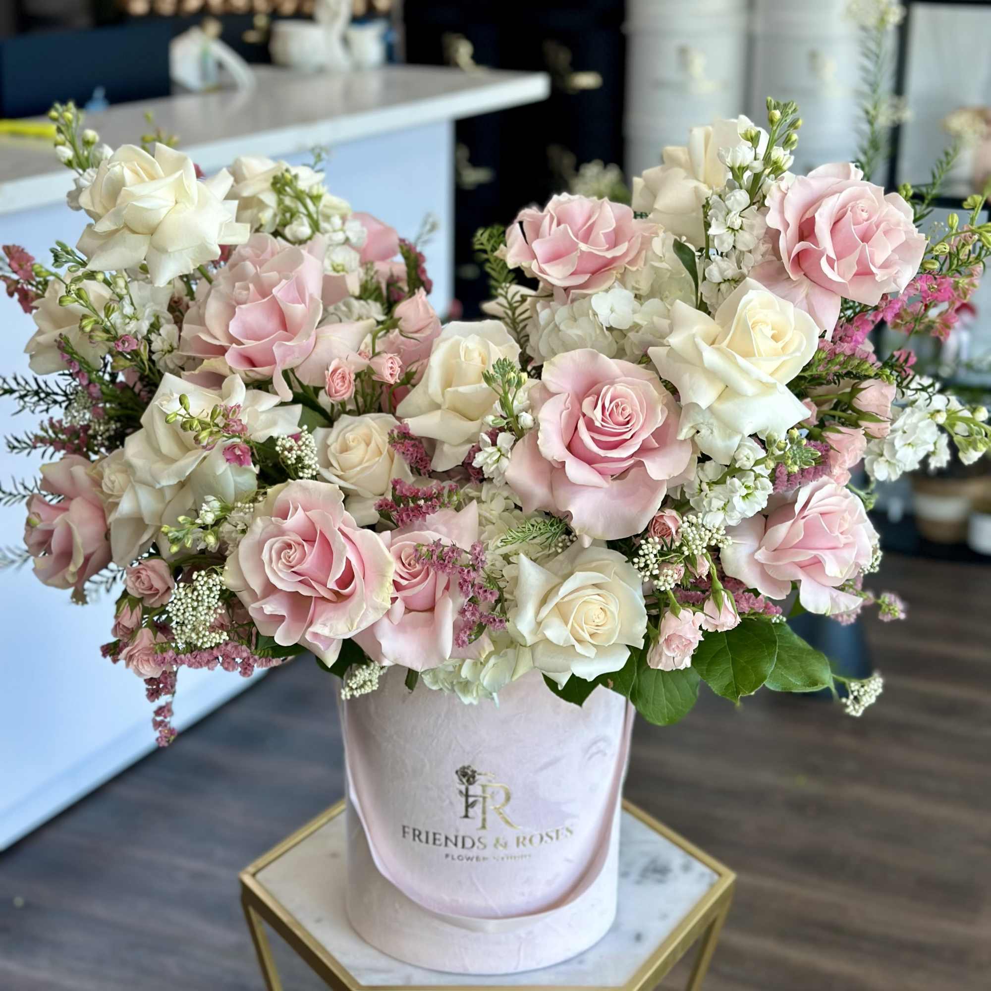 This arrangement, nestled in a chic box, showcases white and pink roses