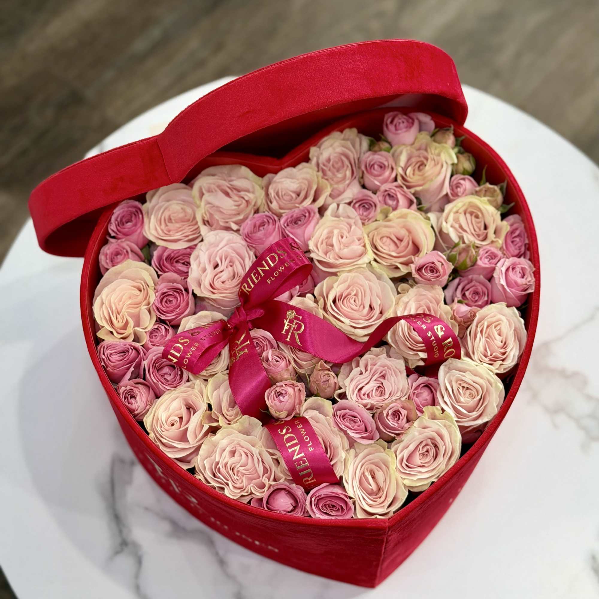 Heart-shaped red box filled with pink and blush roses