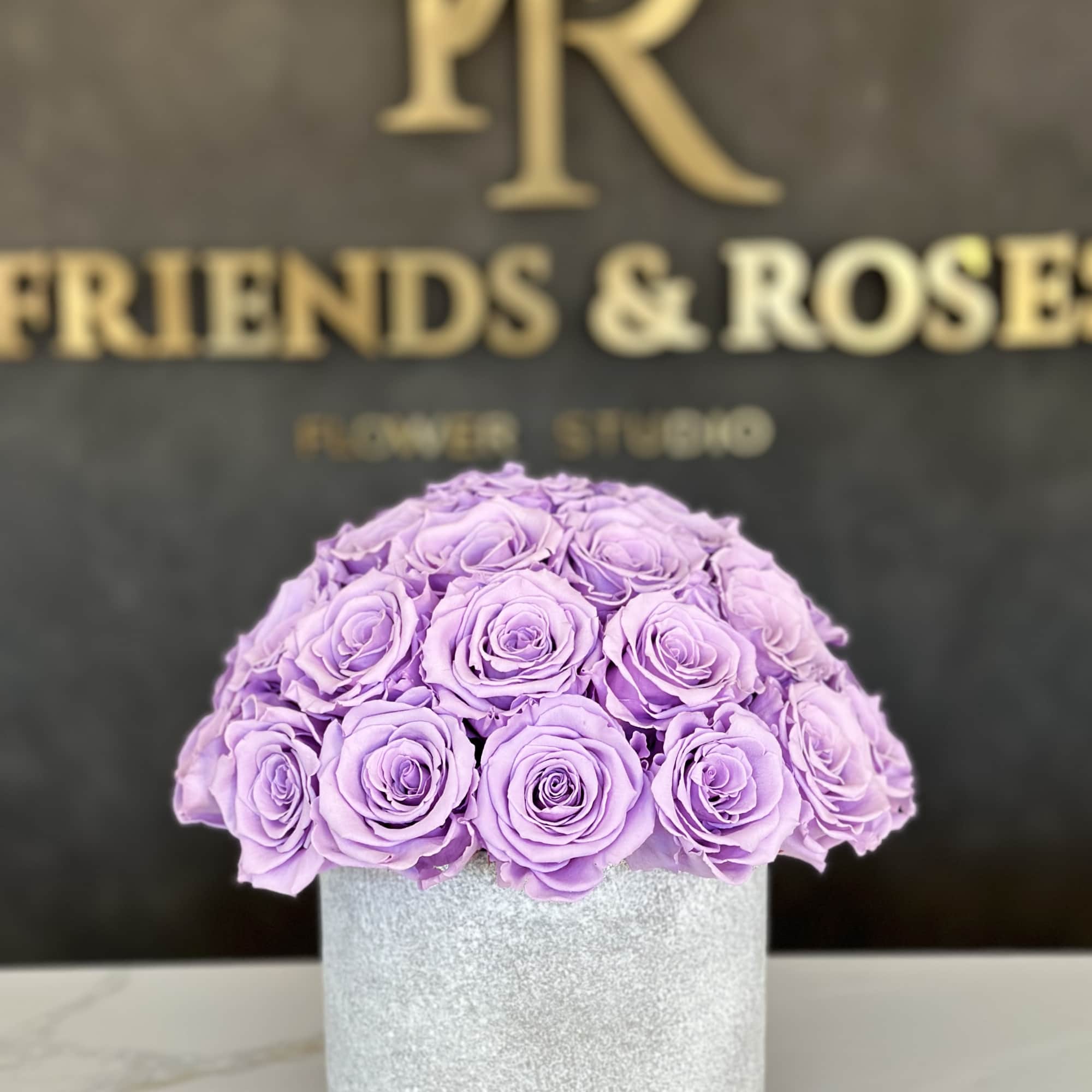 Lavender roses arranged in a round silver box