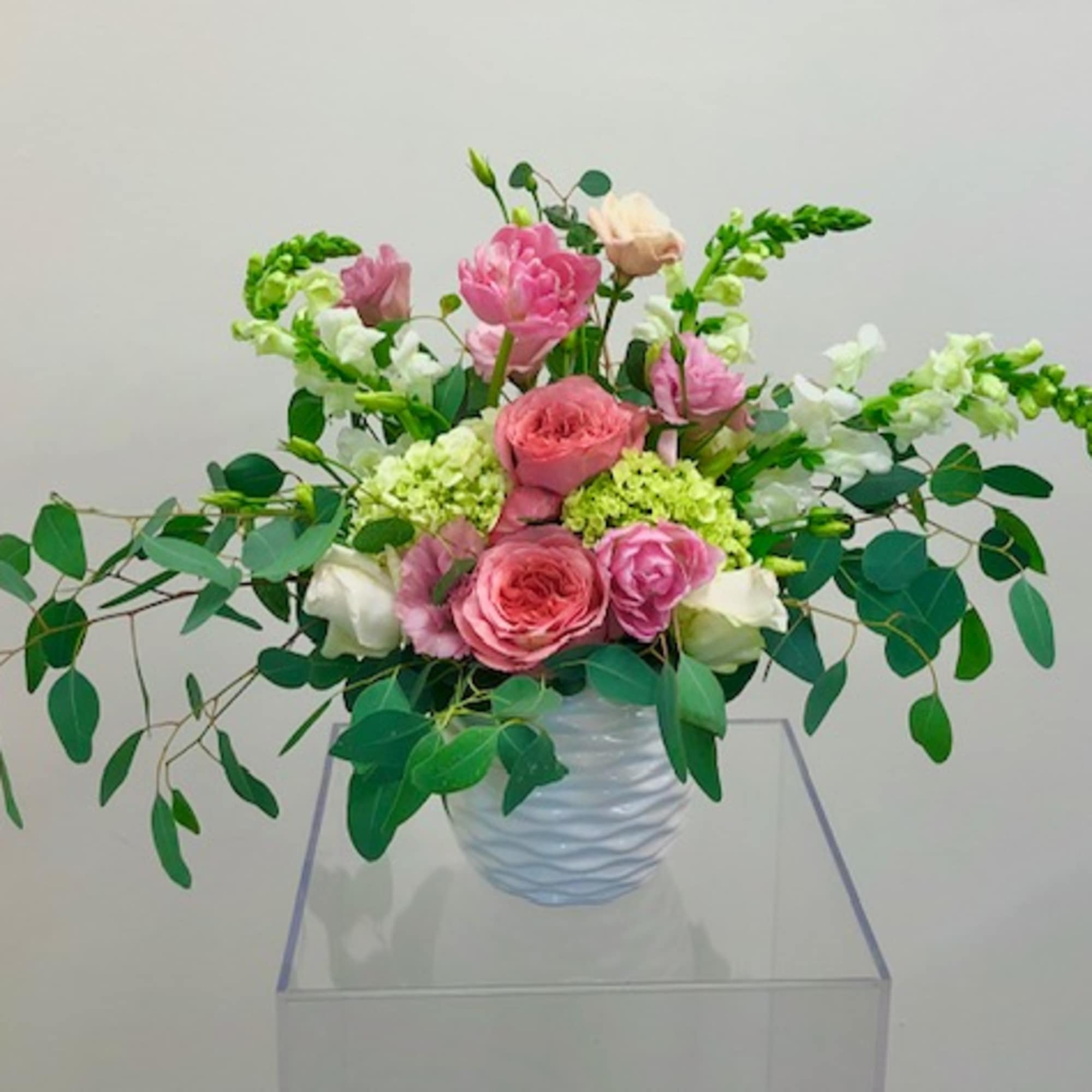 Pink and white rose arrangement in a white vase