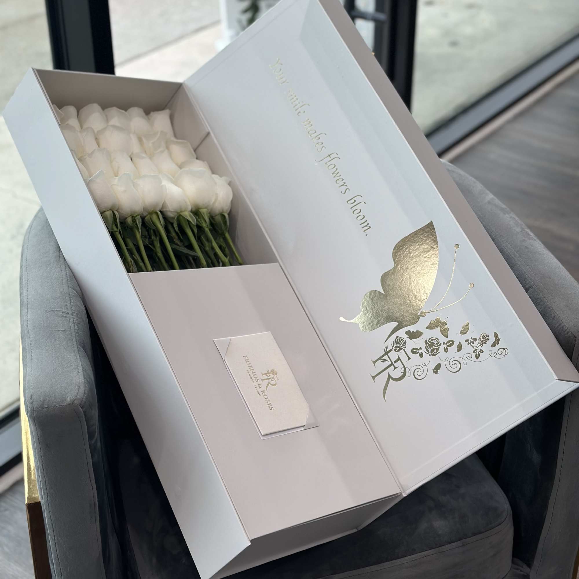 White roses arranged in a presentation box with a gold butterfly design.