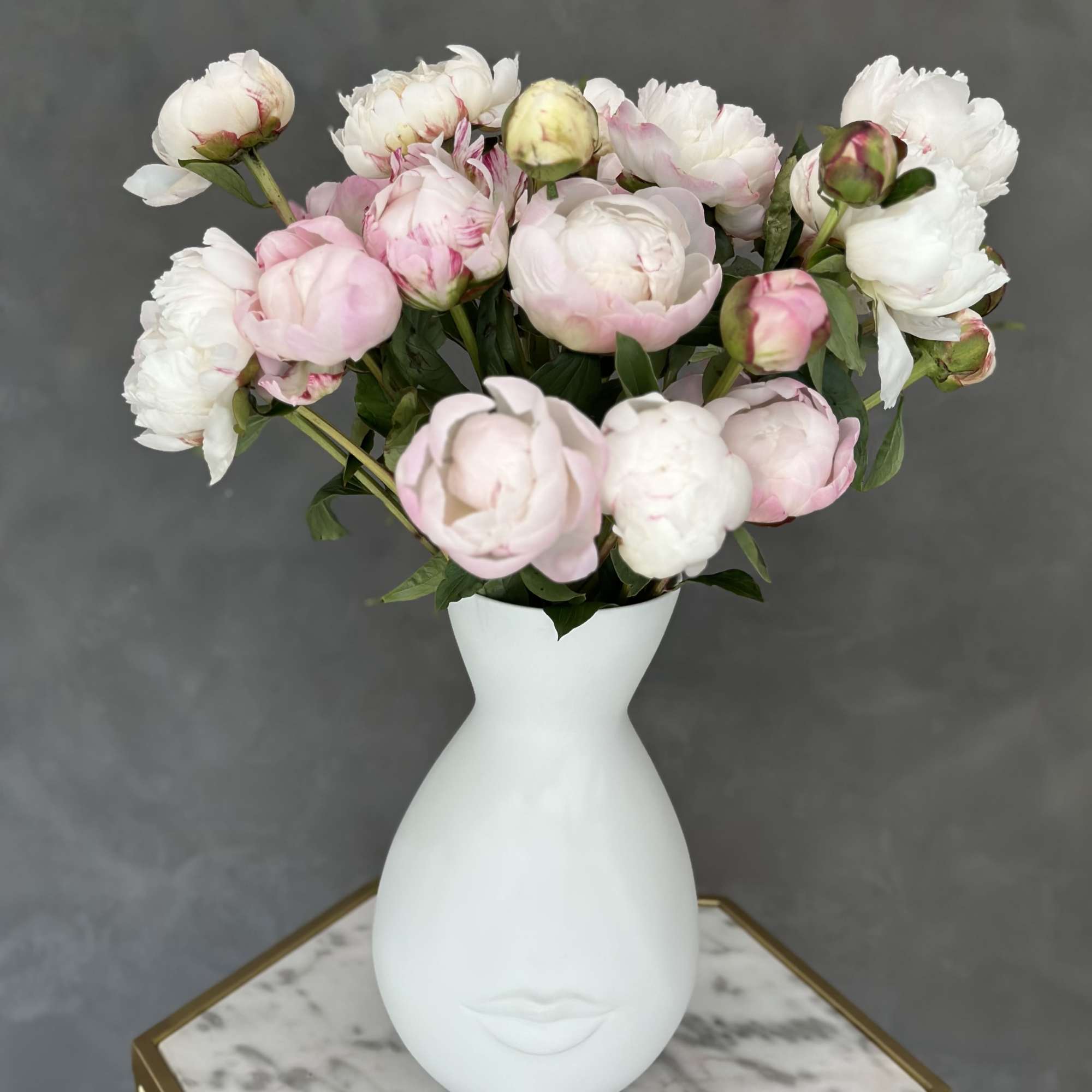 Pink and white peonies arranged in a white vase