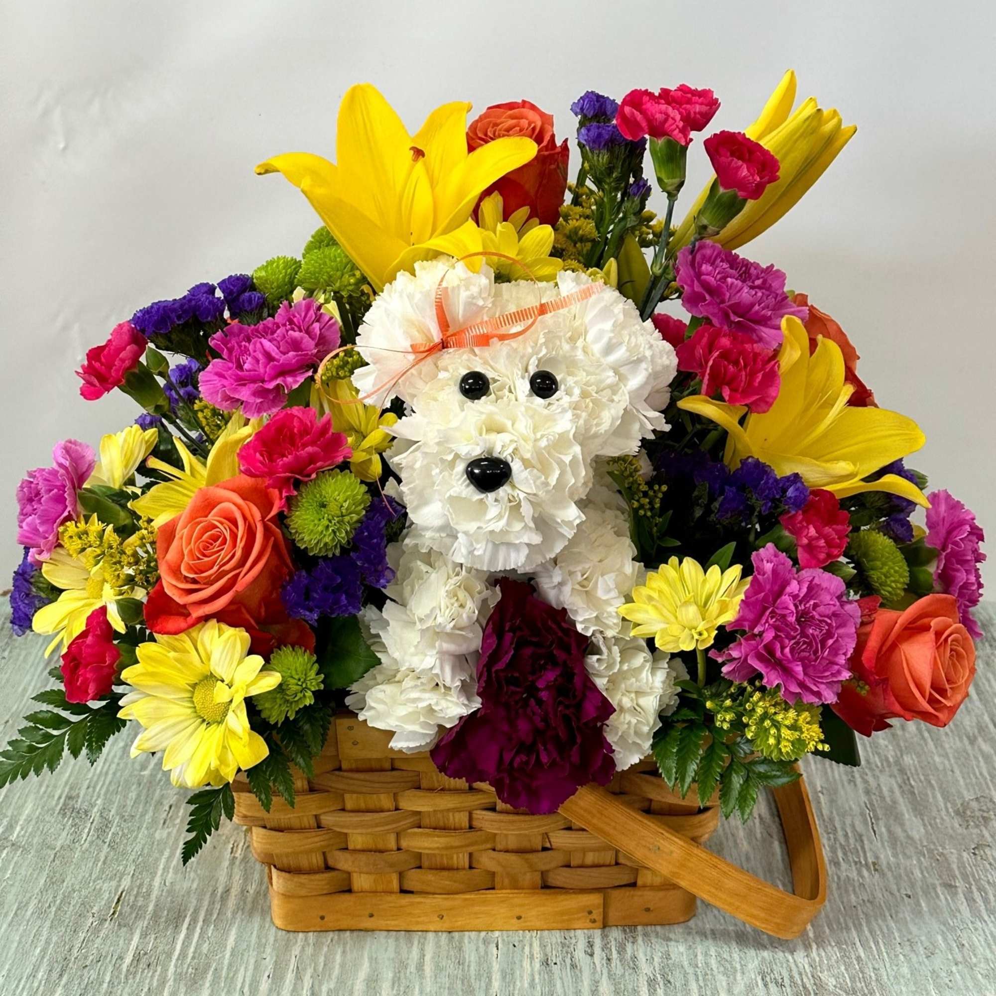 Arrangement of fresh cut flowers designed in a brown rectangular basket. Includes