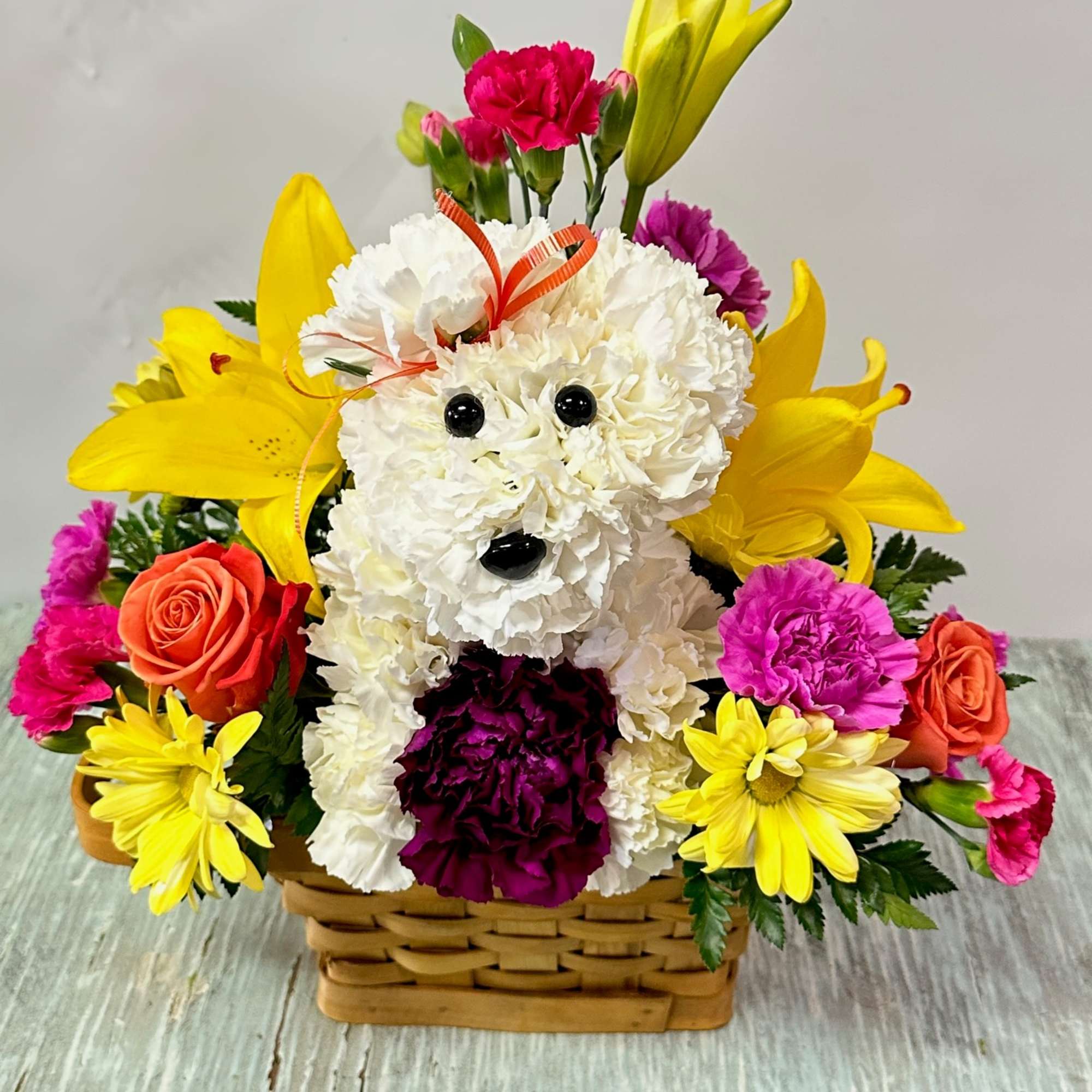 Arrangement of fresh cut flowers designed in a brown rectangular basket. Includes