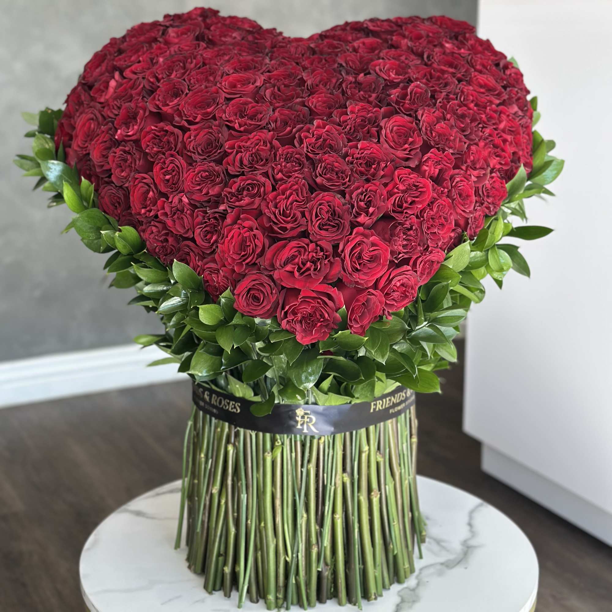 Heart-shaped bouquet of red roses with green foliage and long stems