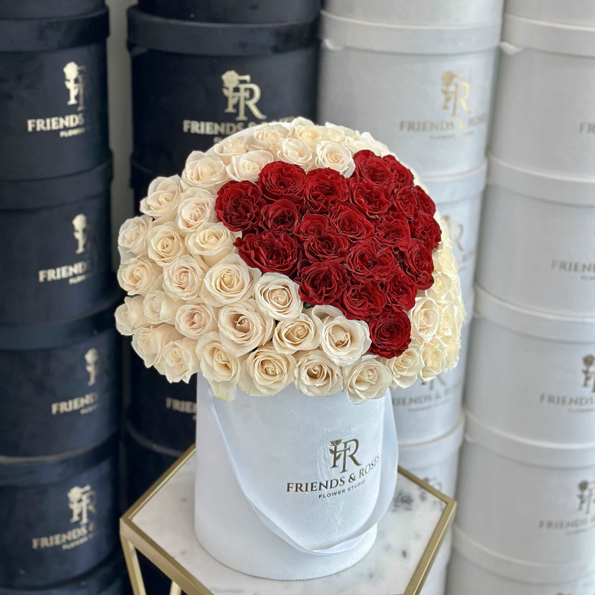 Heart-shaped bouquet of red and cream roses in a white hat box