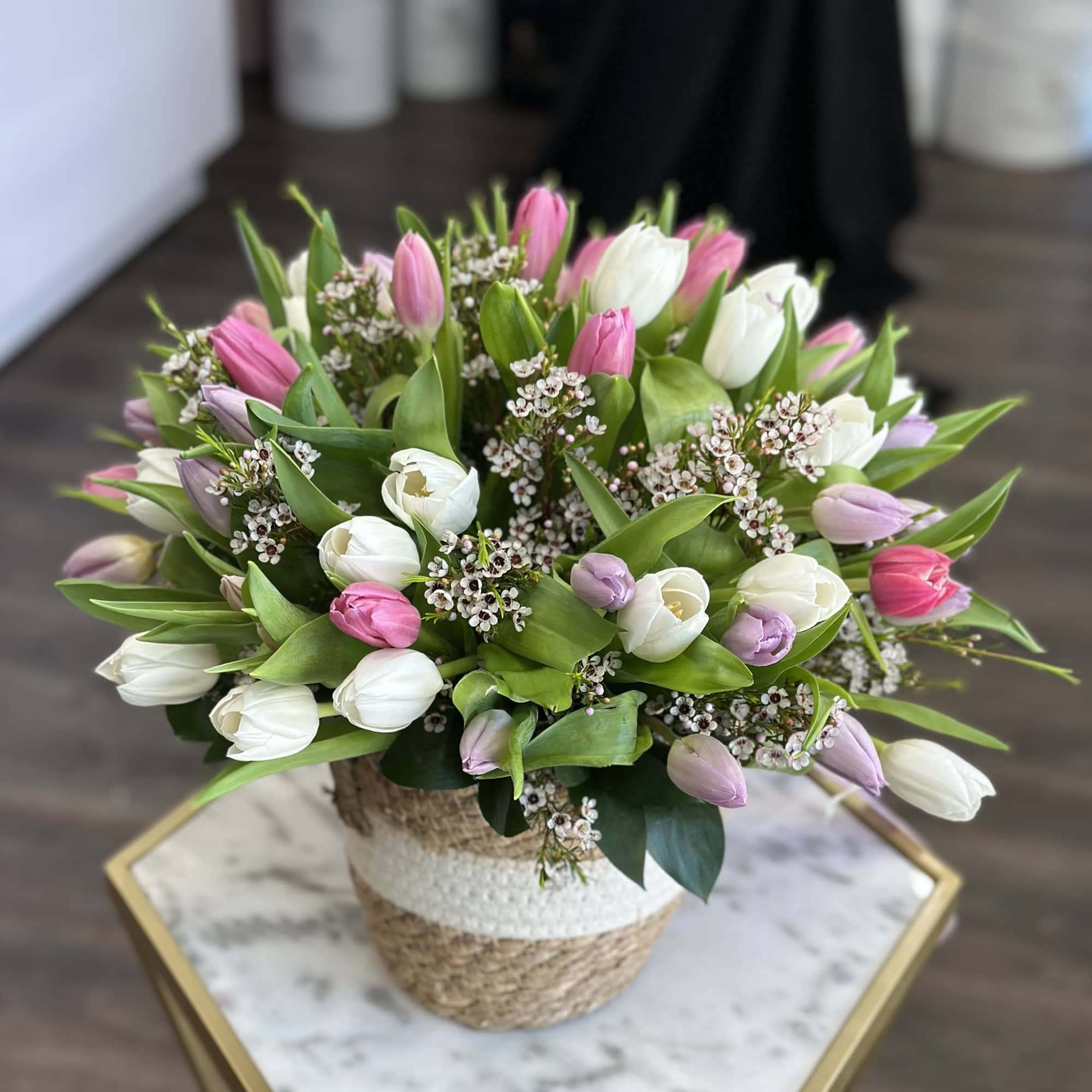 Bouquet of pink and white tulips in a woven basket container