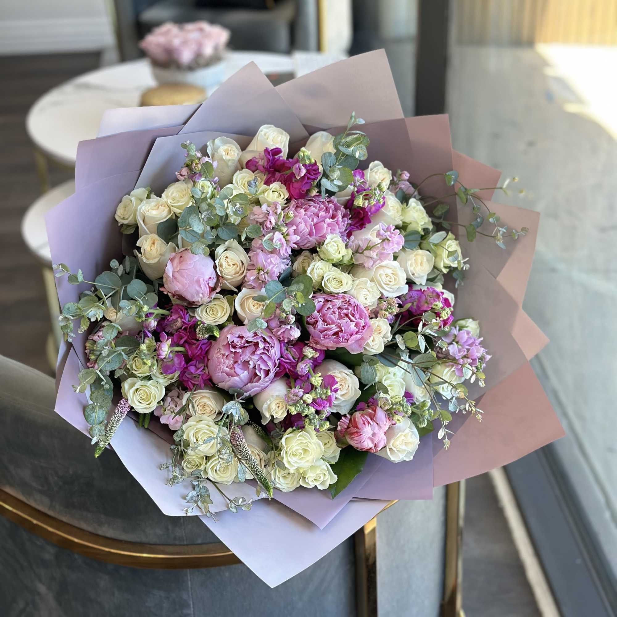 Hand-tied bouquet of pink and white flowers wrapped in pastel paper