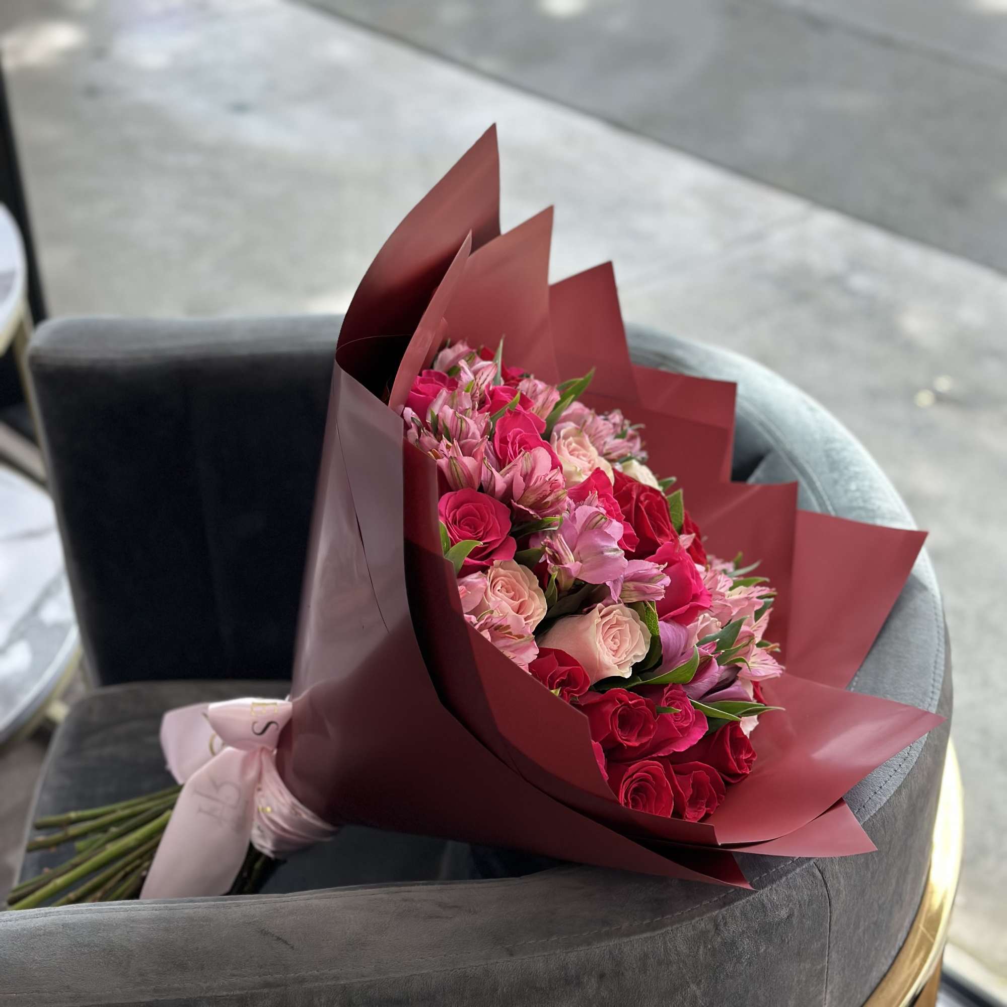 Bouquet of pink and red roses wrapped in burgundy paper