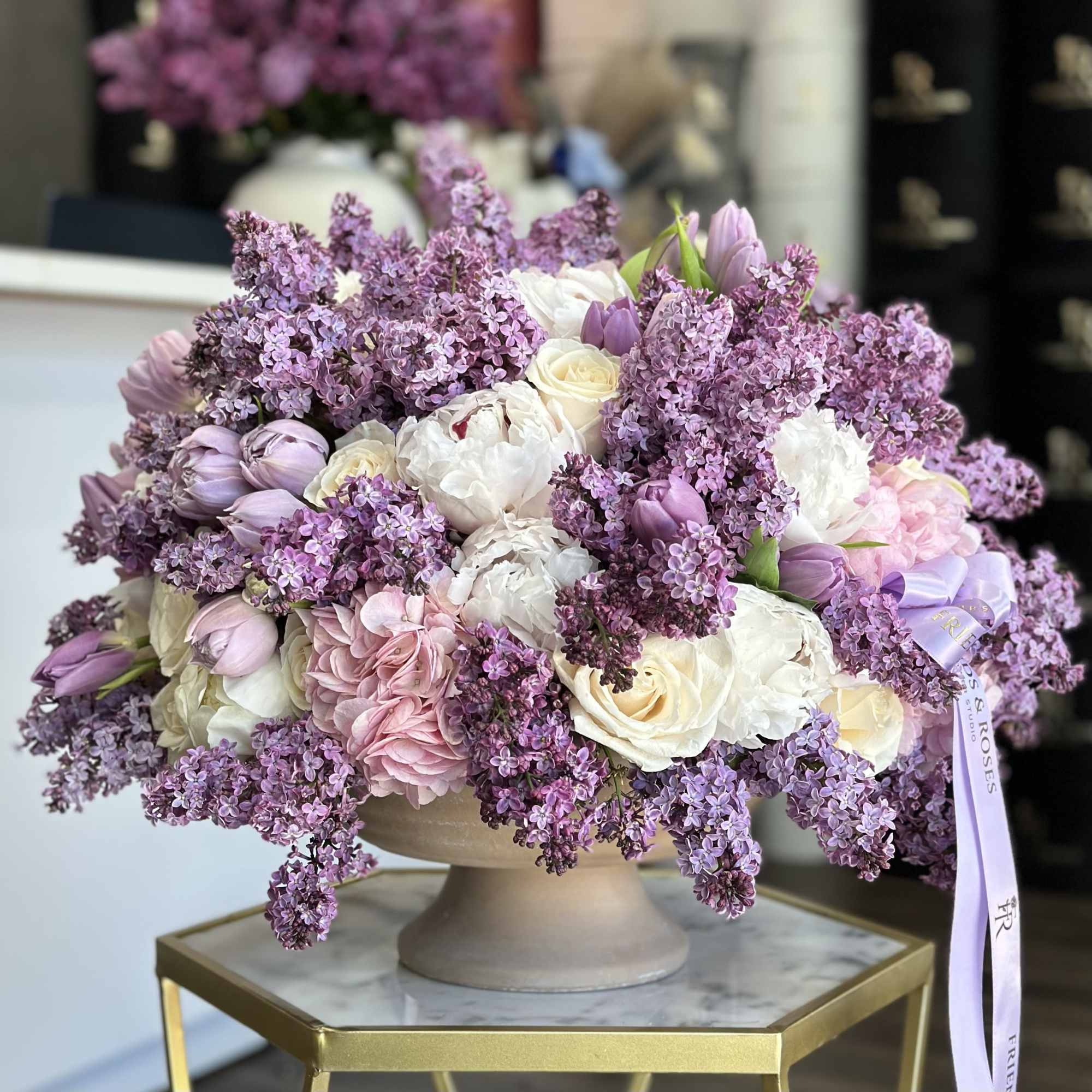 Lavender and white bouquet in a beige pedestal vase