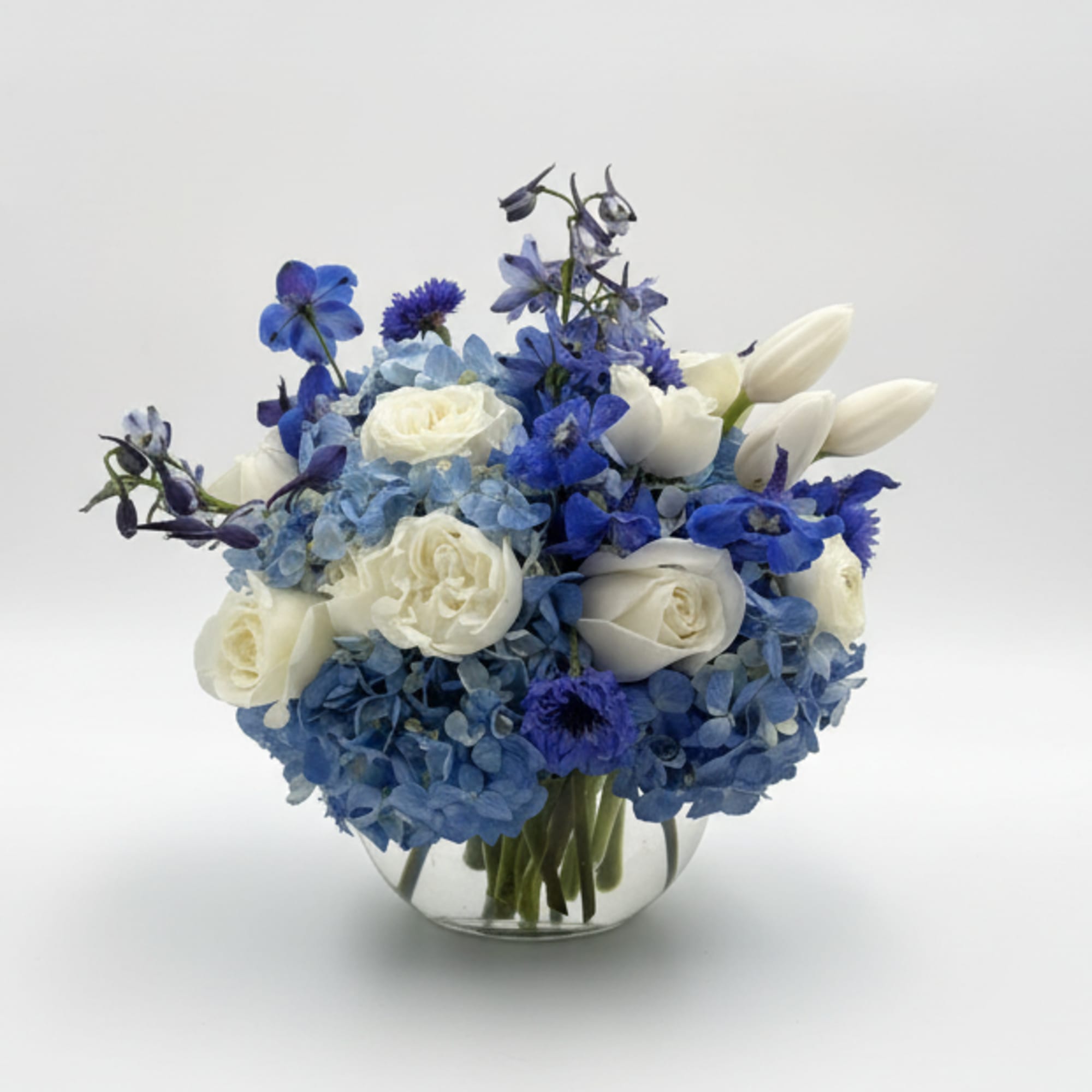 A cool, rounded cluster of blue hydrangeas and creamy white roses makes