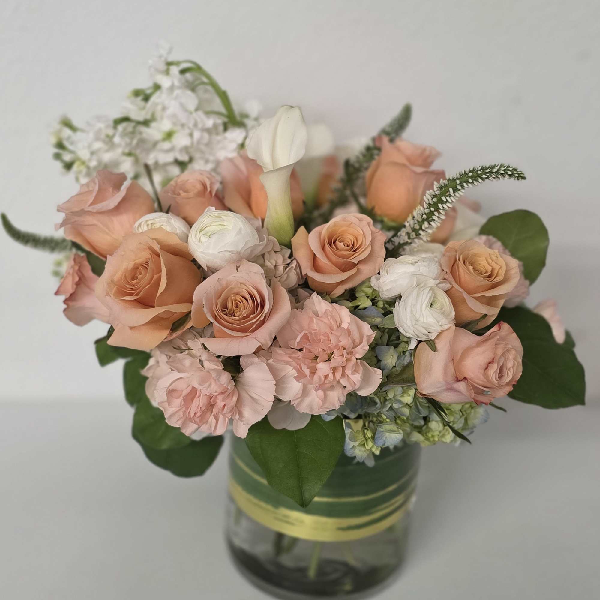 Peach and white flower arrangement in a glass vase