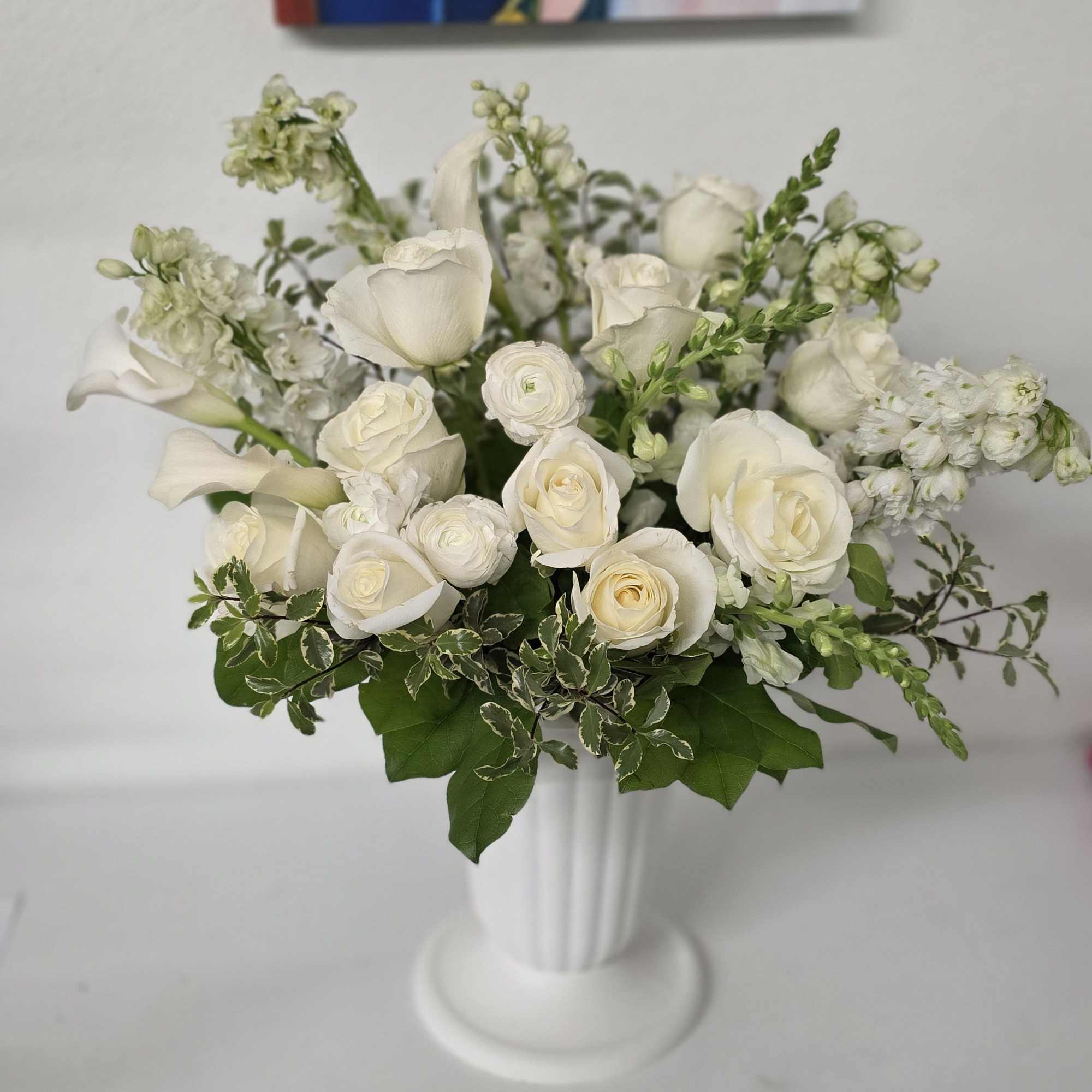 White roses and calla lilies arranged in a white vase
