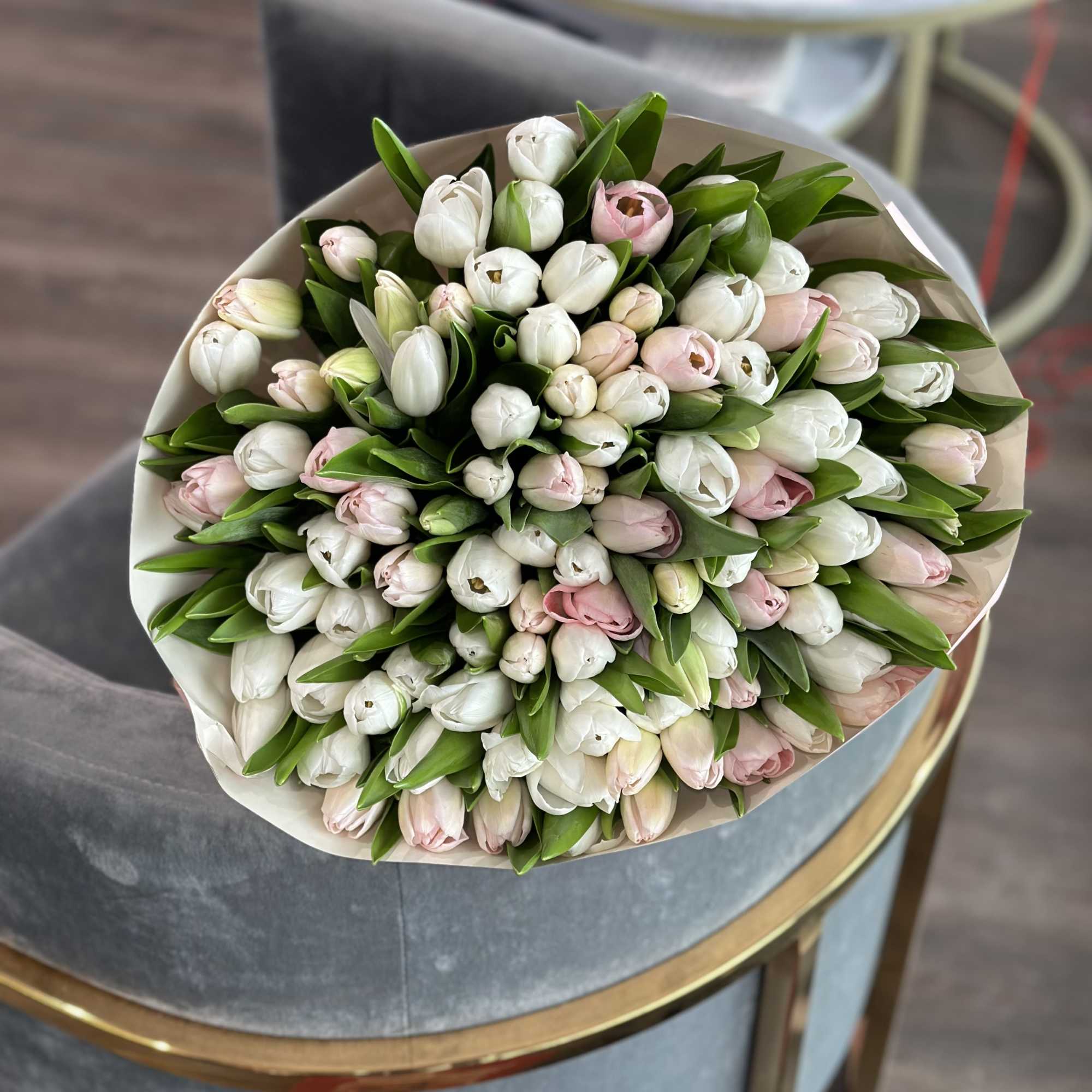 Bouquet of white and pale pink tulips wrapped in beige paper