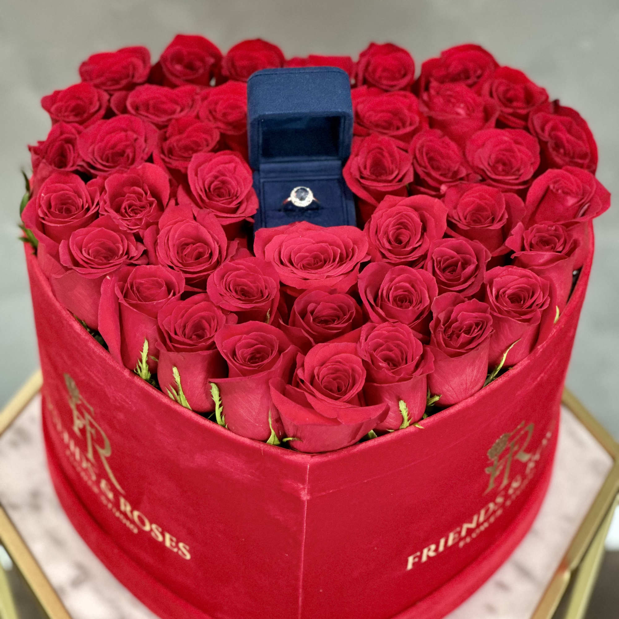 Heart-shaped box of red roses with a ring box in the center