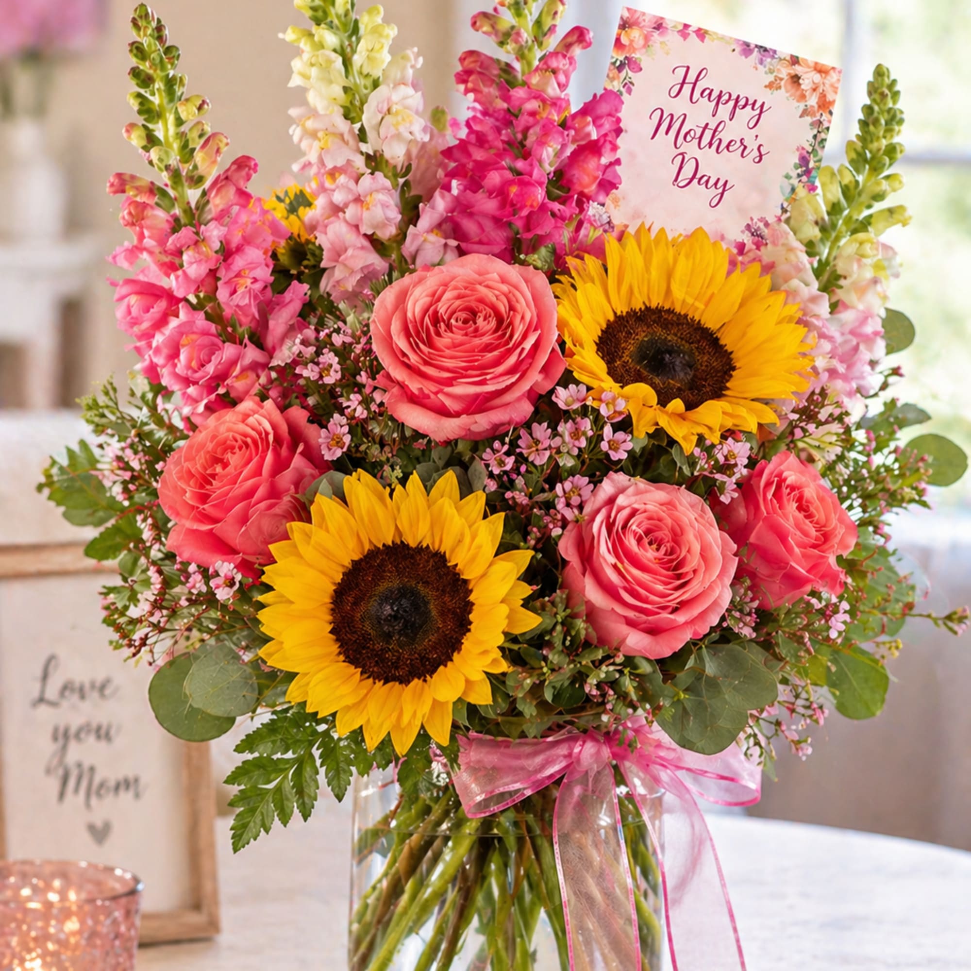 A vibrant mix of golden sunflowers, soft pink roses, and cheerful snapdragons