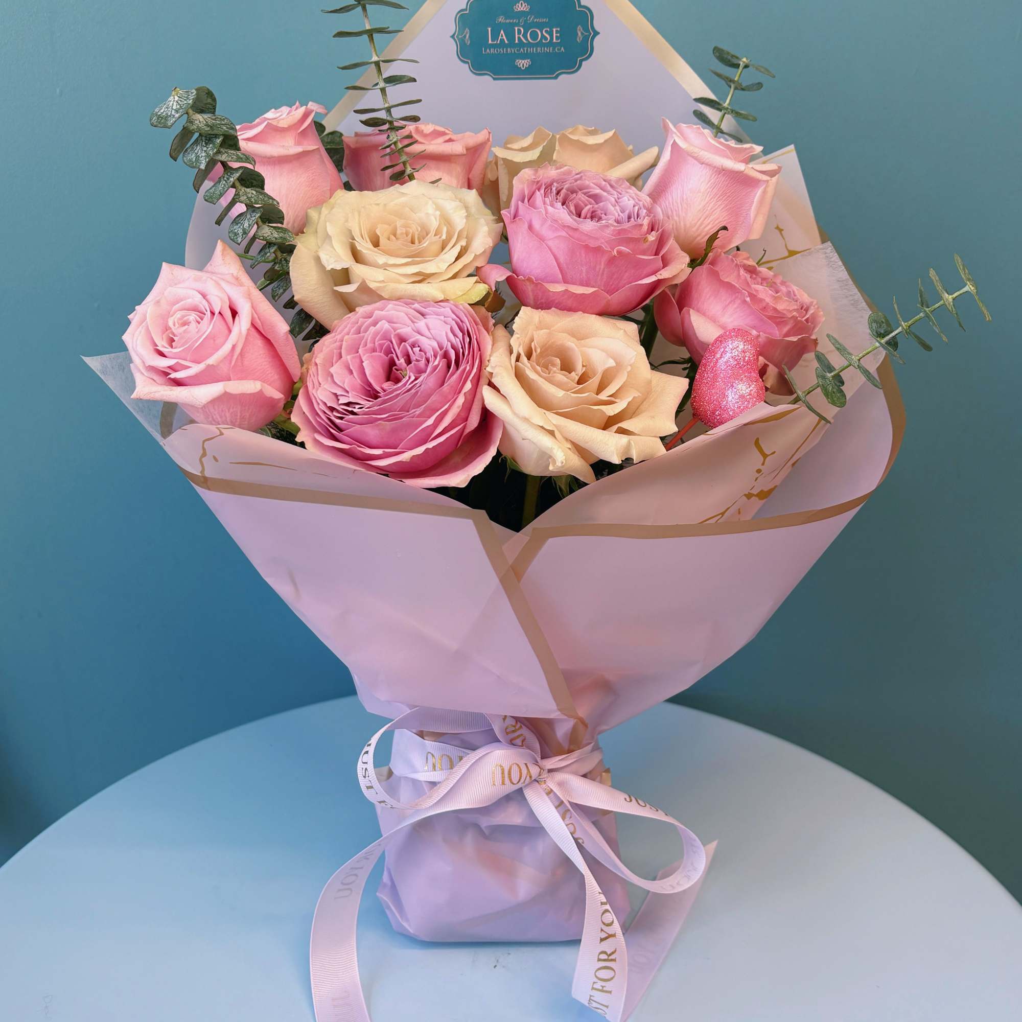 Pink and cream rose bouquet wrapped in pastel paper with a ribbon