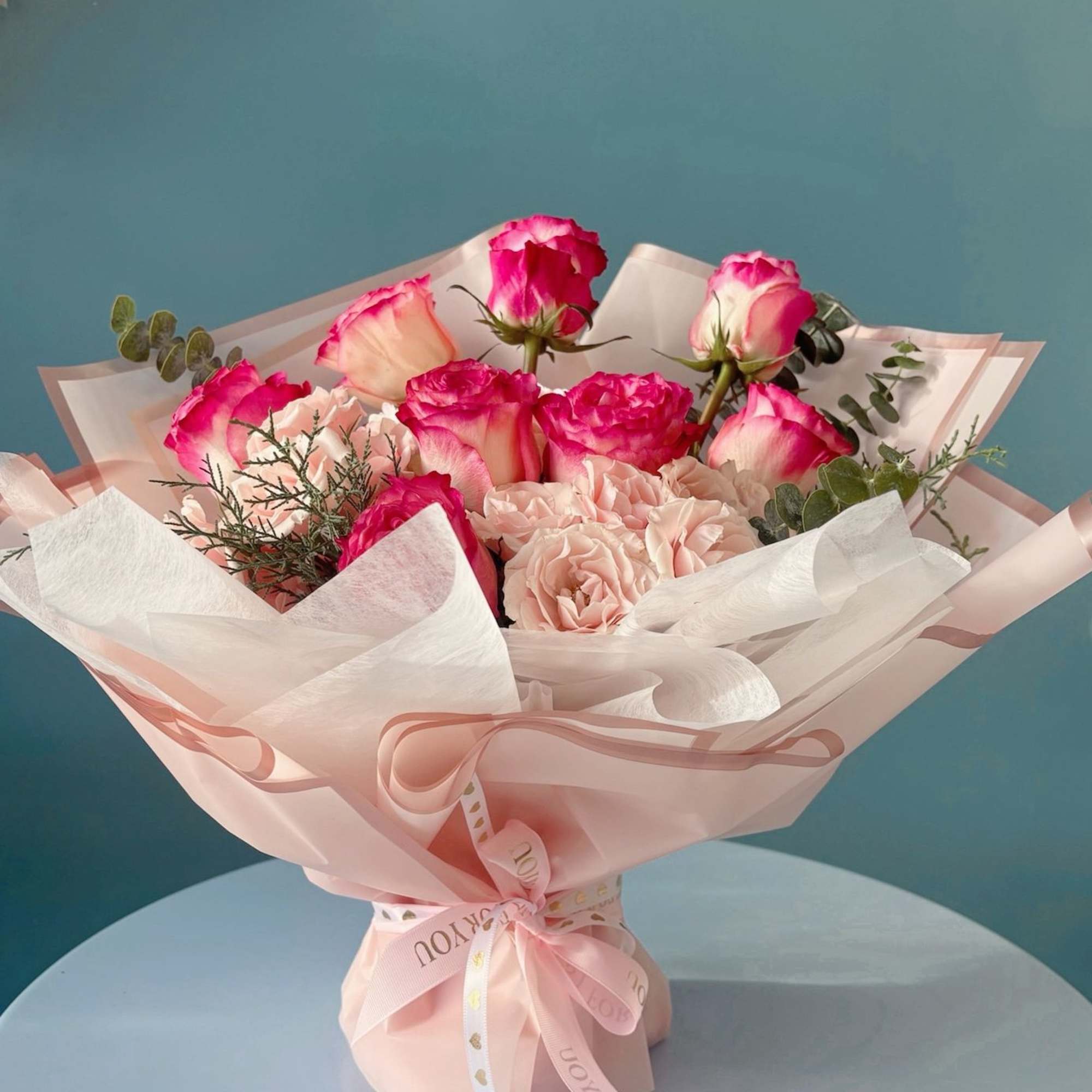 Pink and white rose bouquet wrapped in pale pink paper