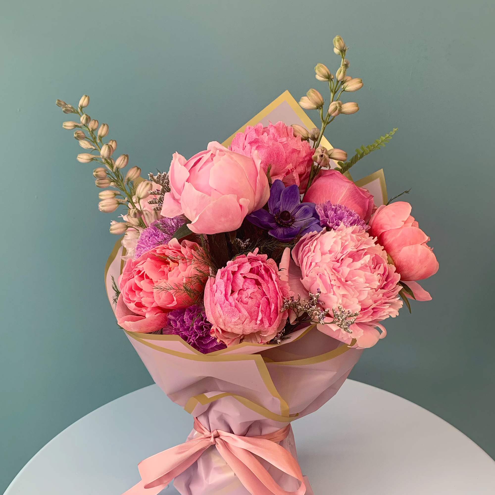 Pink and purple mixed bouquet wrapped in pastel paper with a ribbon