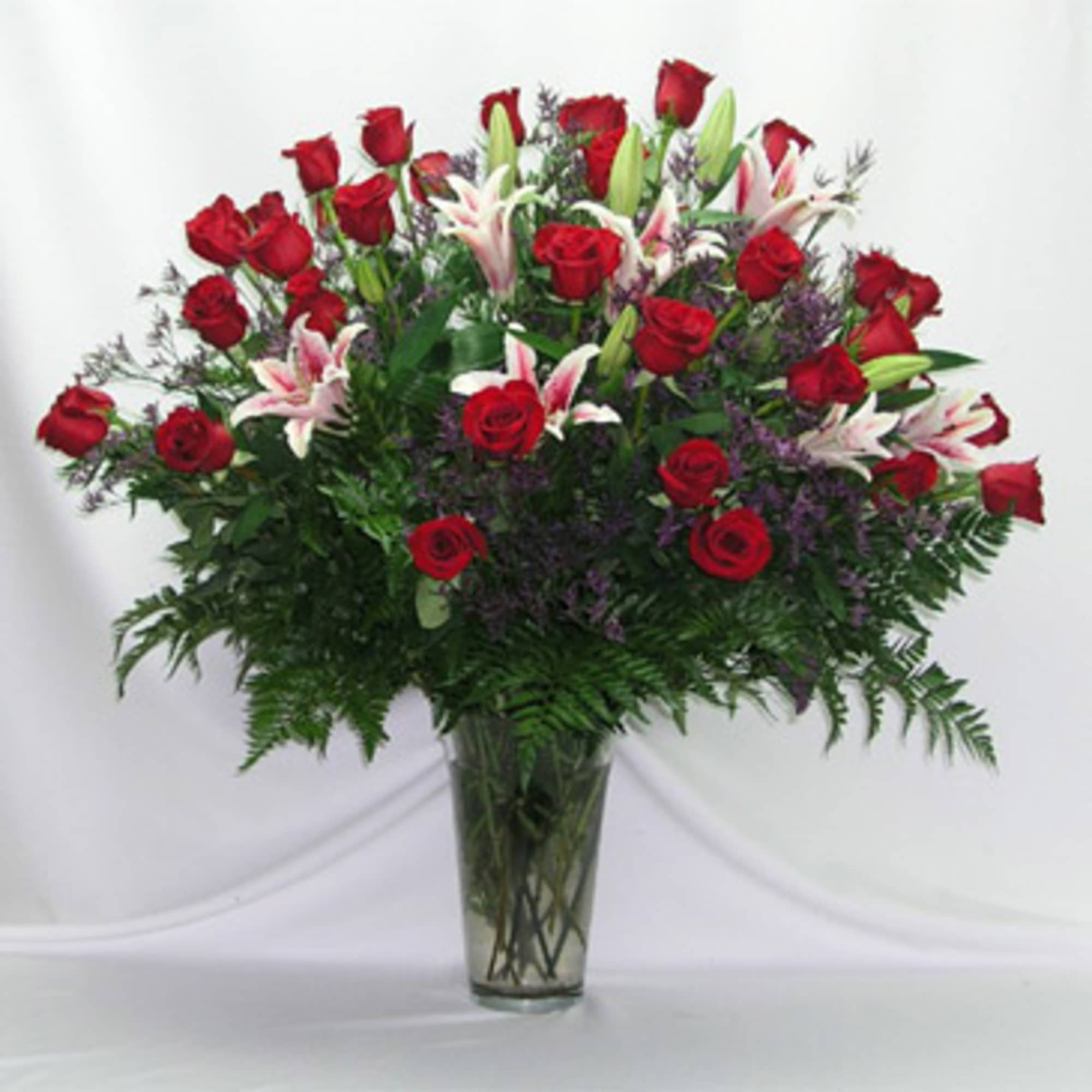 Large bouquet of red roses and pink lilies in a clear glass vase