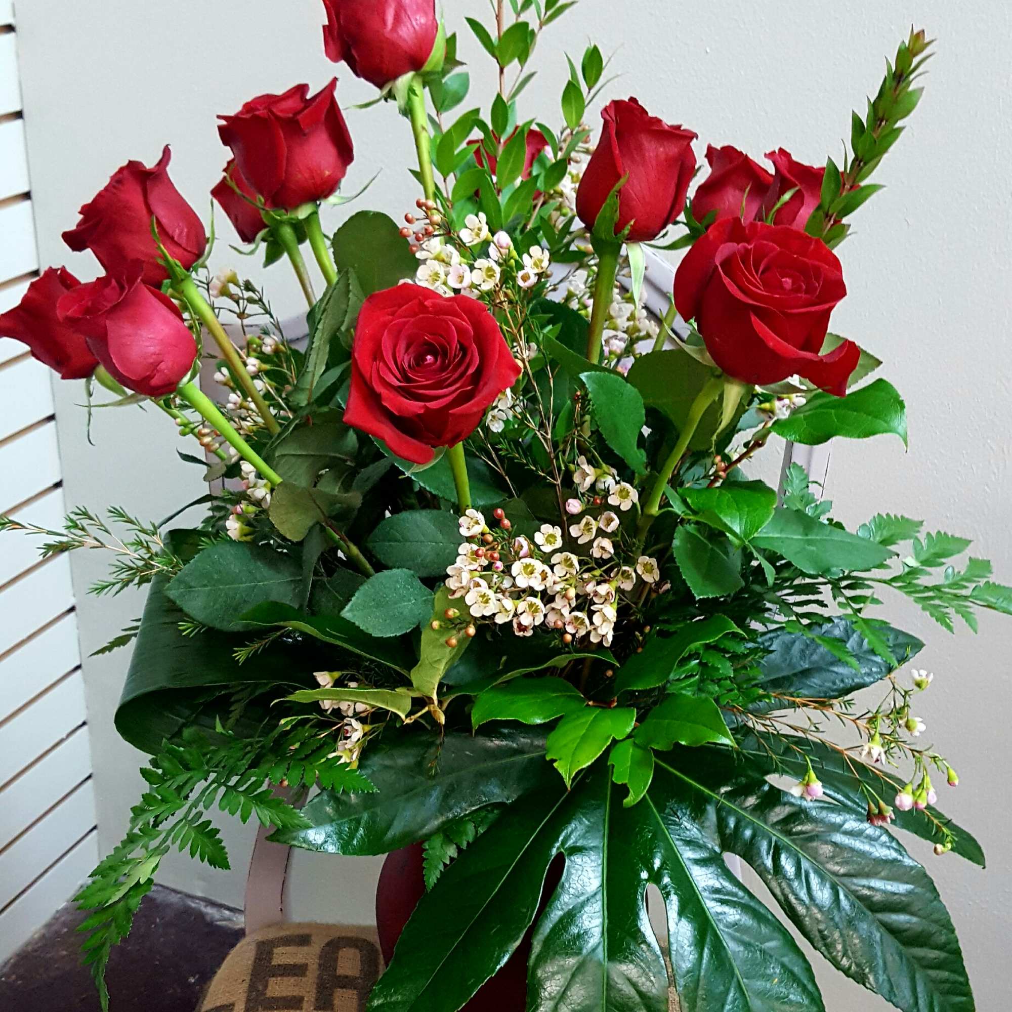 Red roses arranged in a vase with small white filler flowers and greenery
