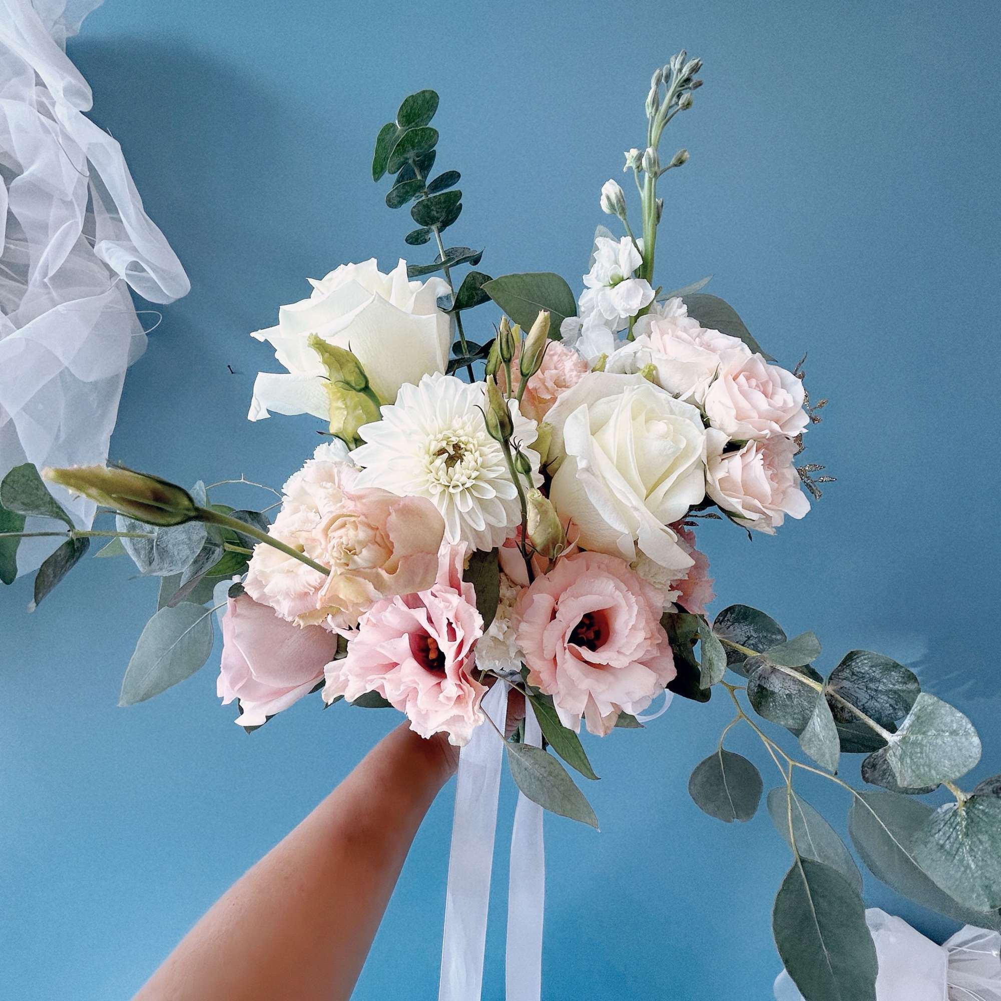 Wedding bouquet of white and blush flowers with trailing eucalyptus
