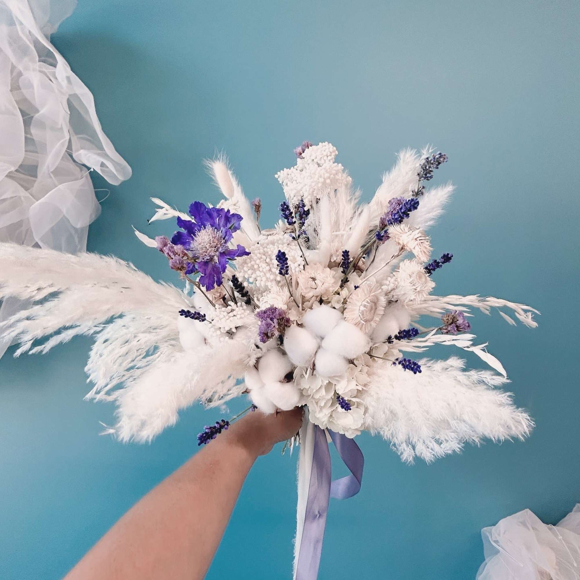 White and purple bridal bouquet with fluffy dried accents and ribbon