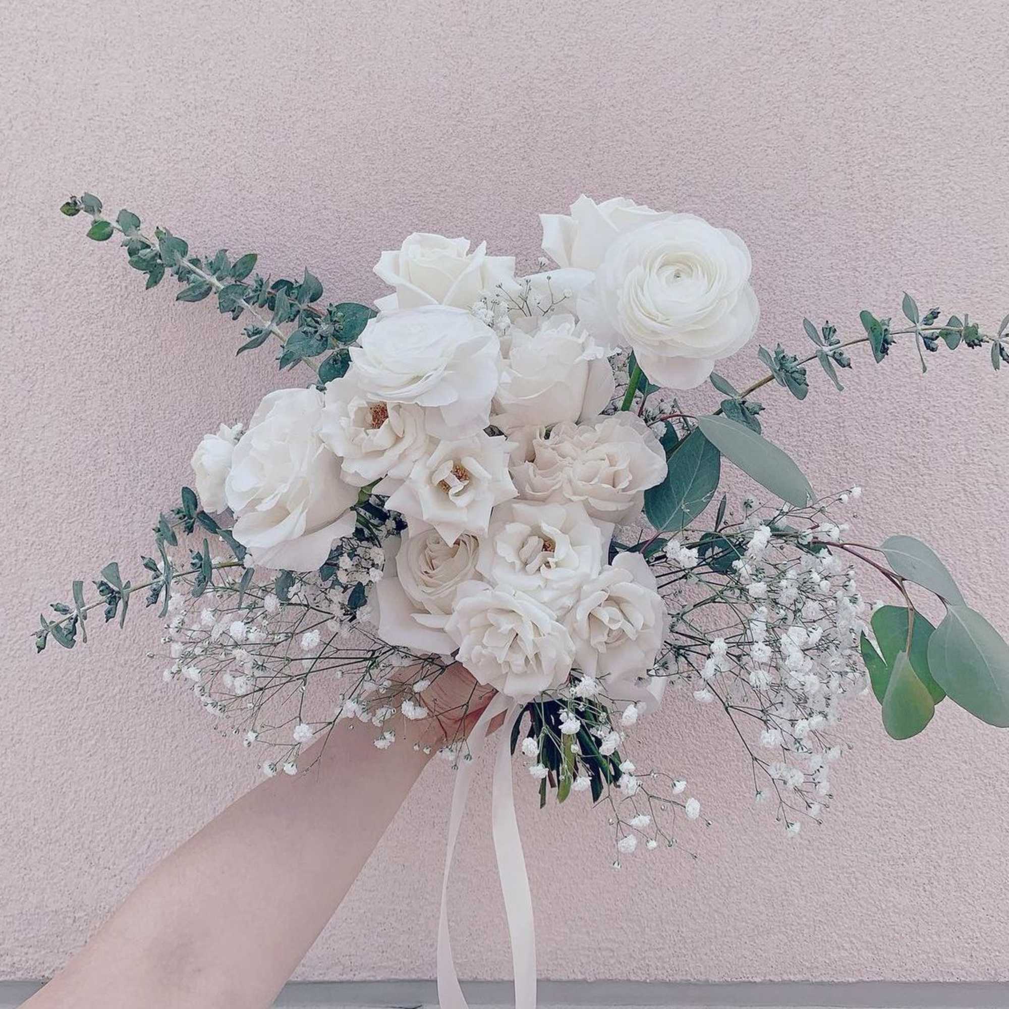 White bridal bouquet with roses and ranunculus, accented by eucalyptus and baby's breath
