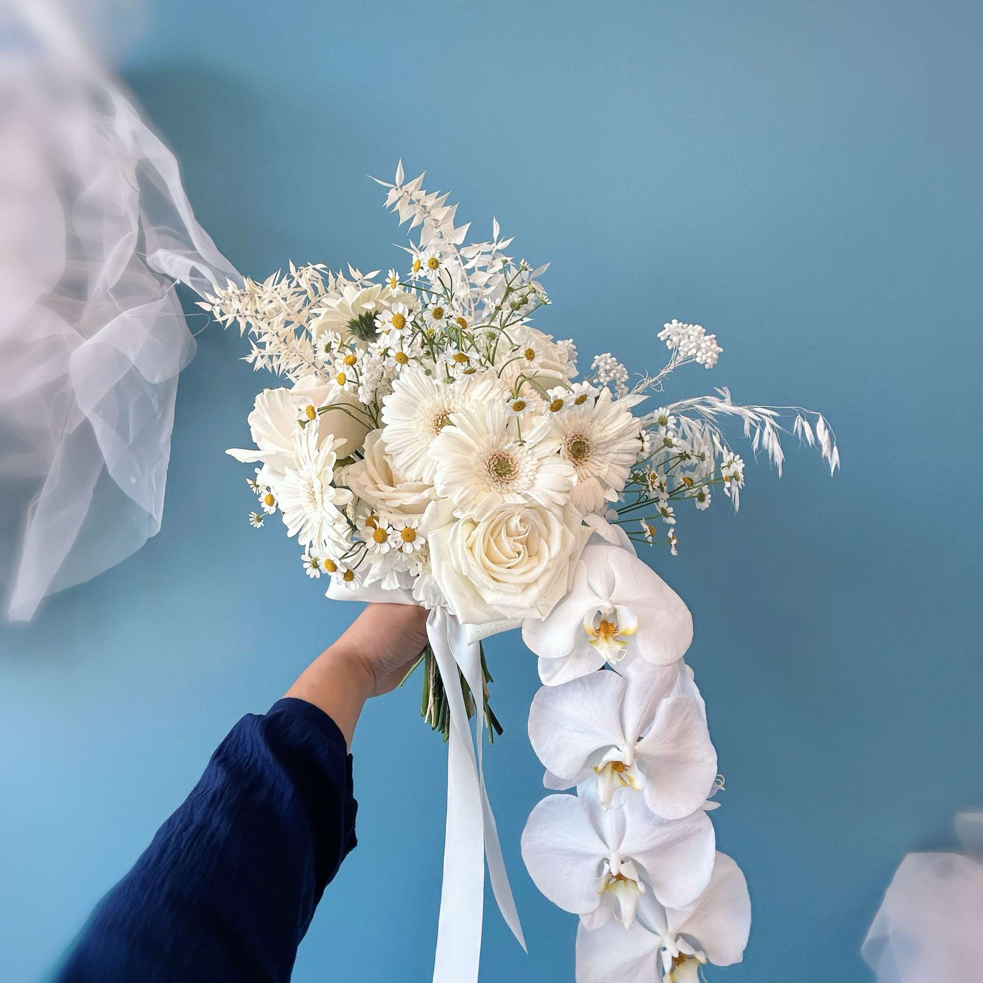 White bridal bouquet with roses, daisies, and cascading orchids
