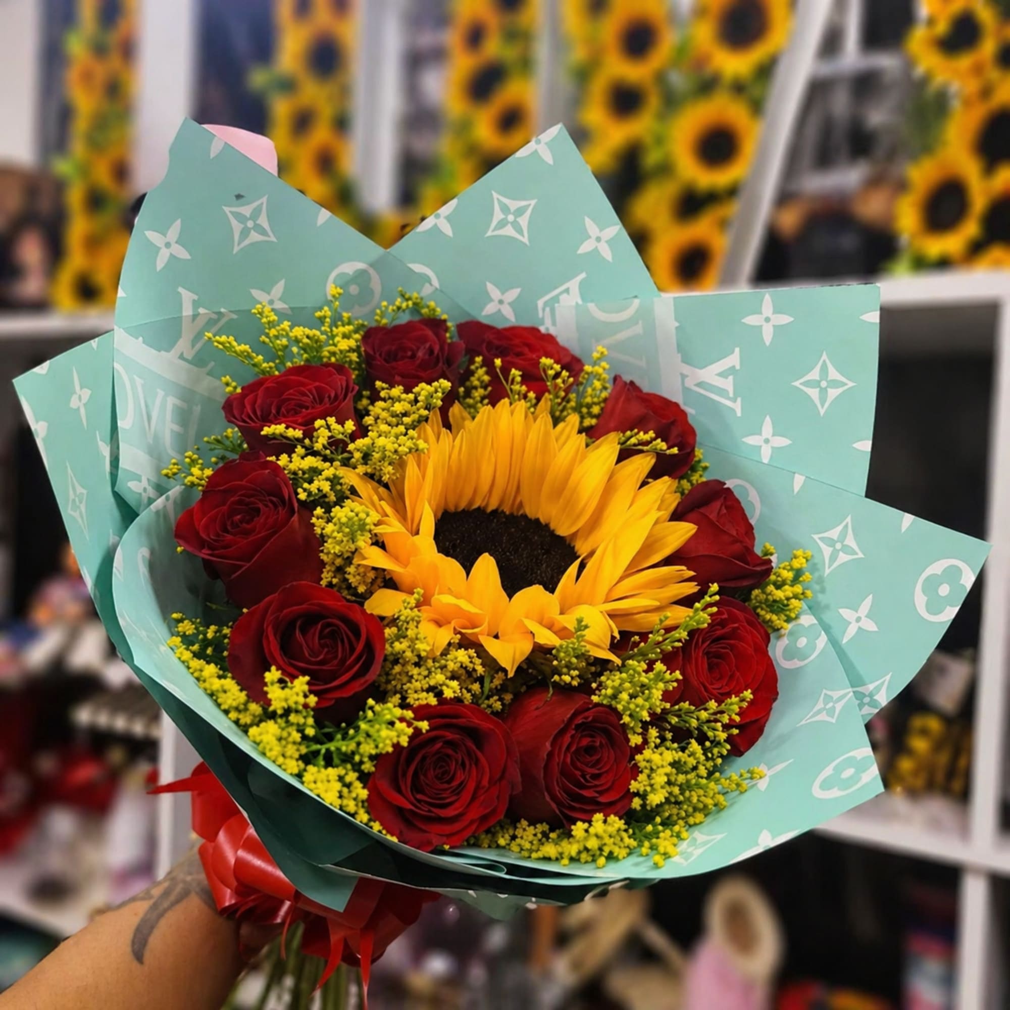 A single radiant sunflower anchors this flower arrangement, its warm yellow face