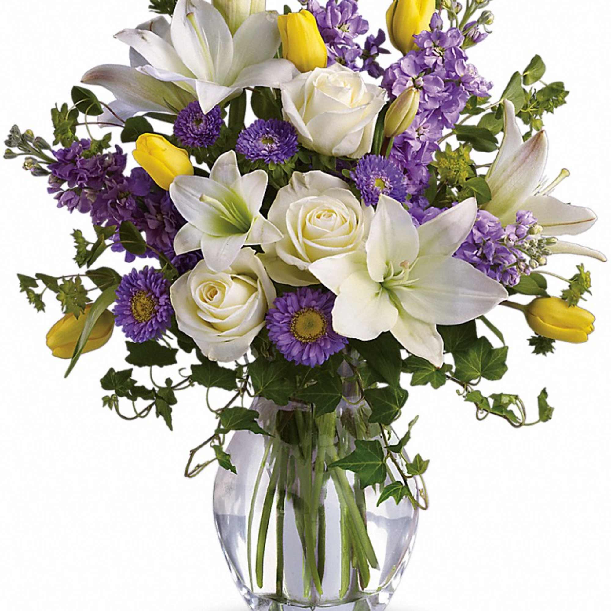 White lilies, roses, purple flowers, and yellow tulips in a glass vase
