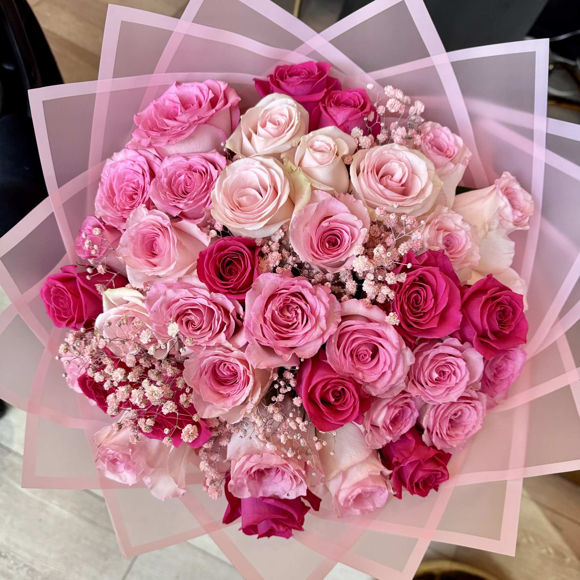 Bouquet of pink and white roses wrapped in translucent pink paper