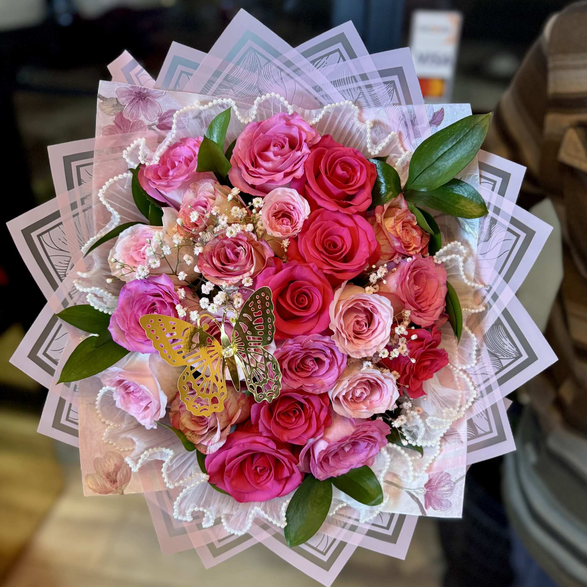 Pink and red rose bouquet with decorative wrapping and a butterfly accent