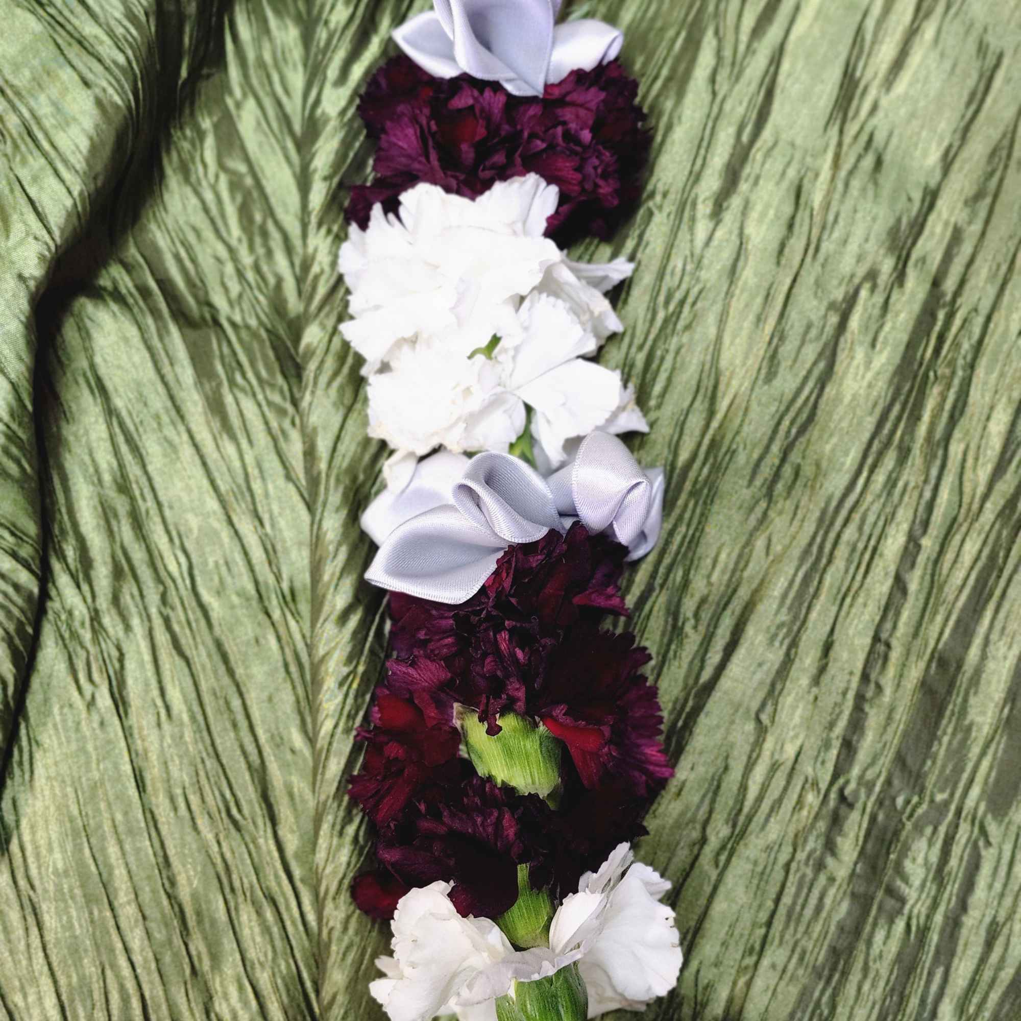 White and burgundy carnation lei with lavender ribbon accents