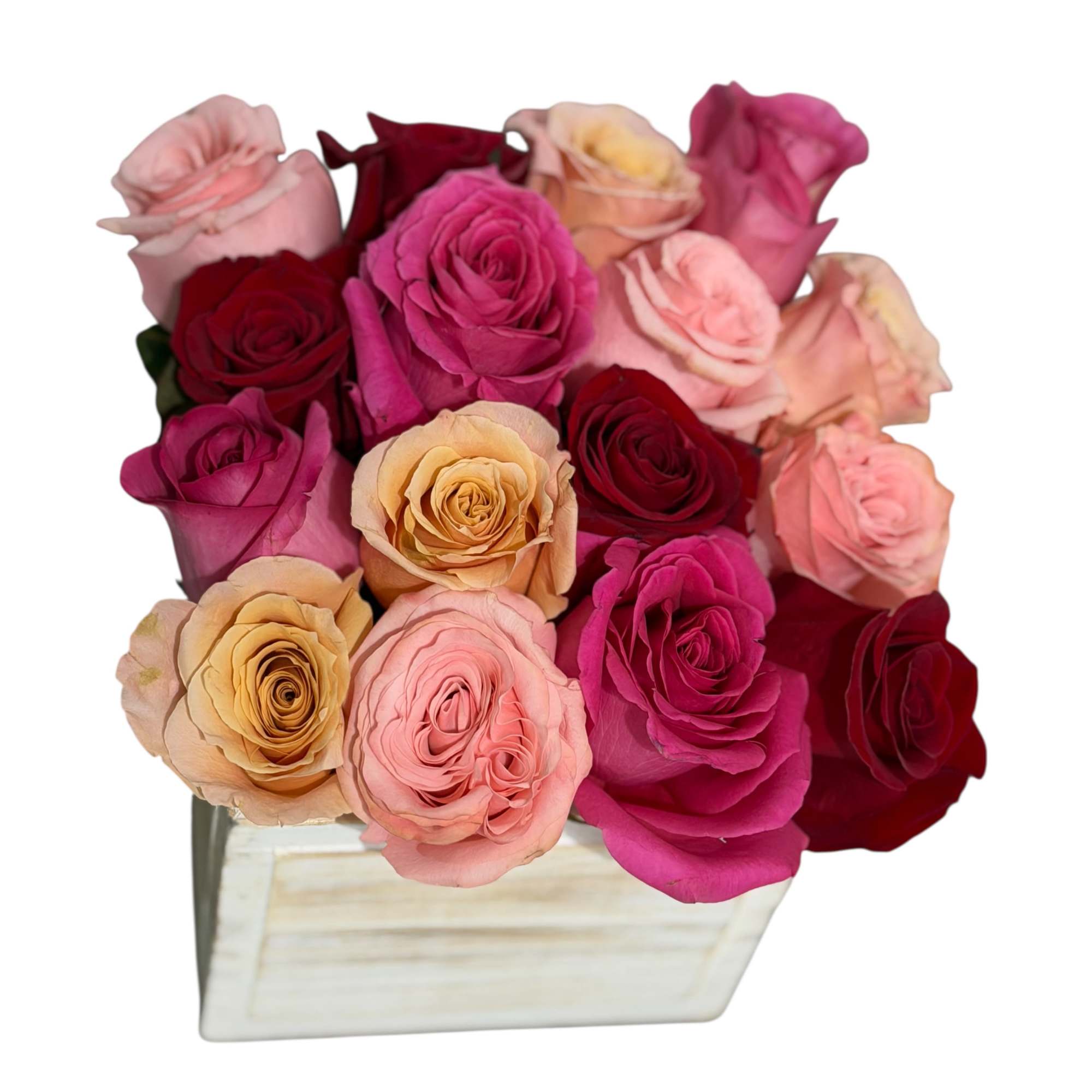 Mixed roses in pink, red, and peach arranged in a white rectangular vase