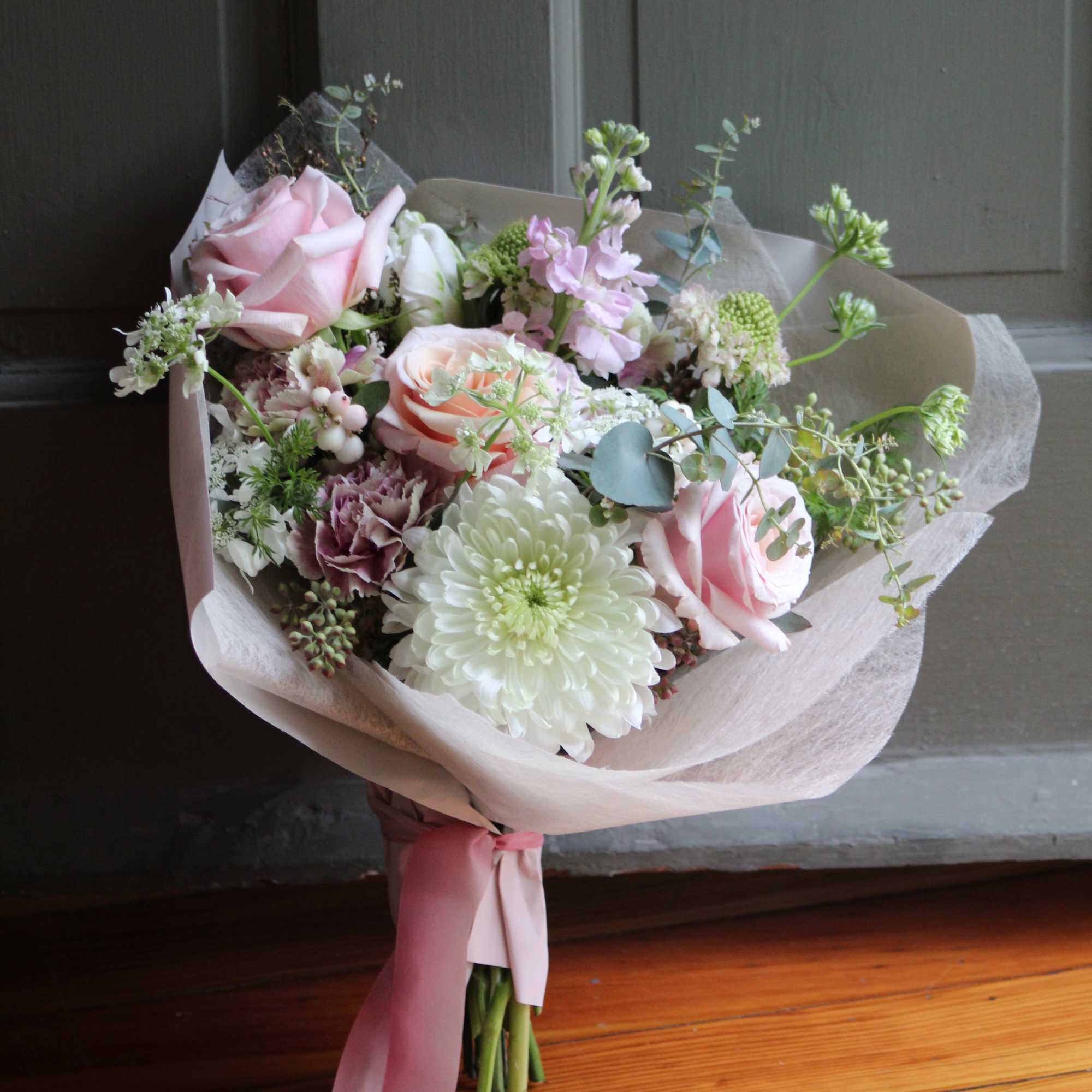 Bouquet of pink roses and white chrysanthemums wrapped in pale paper