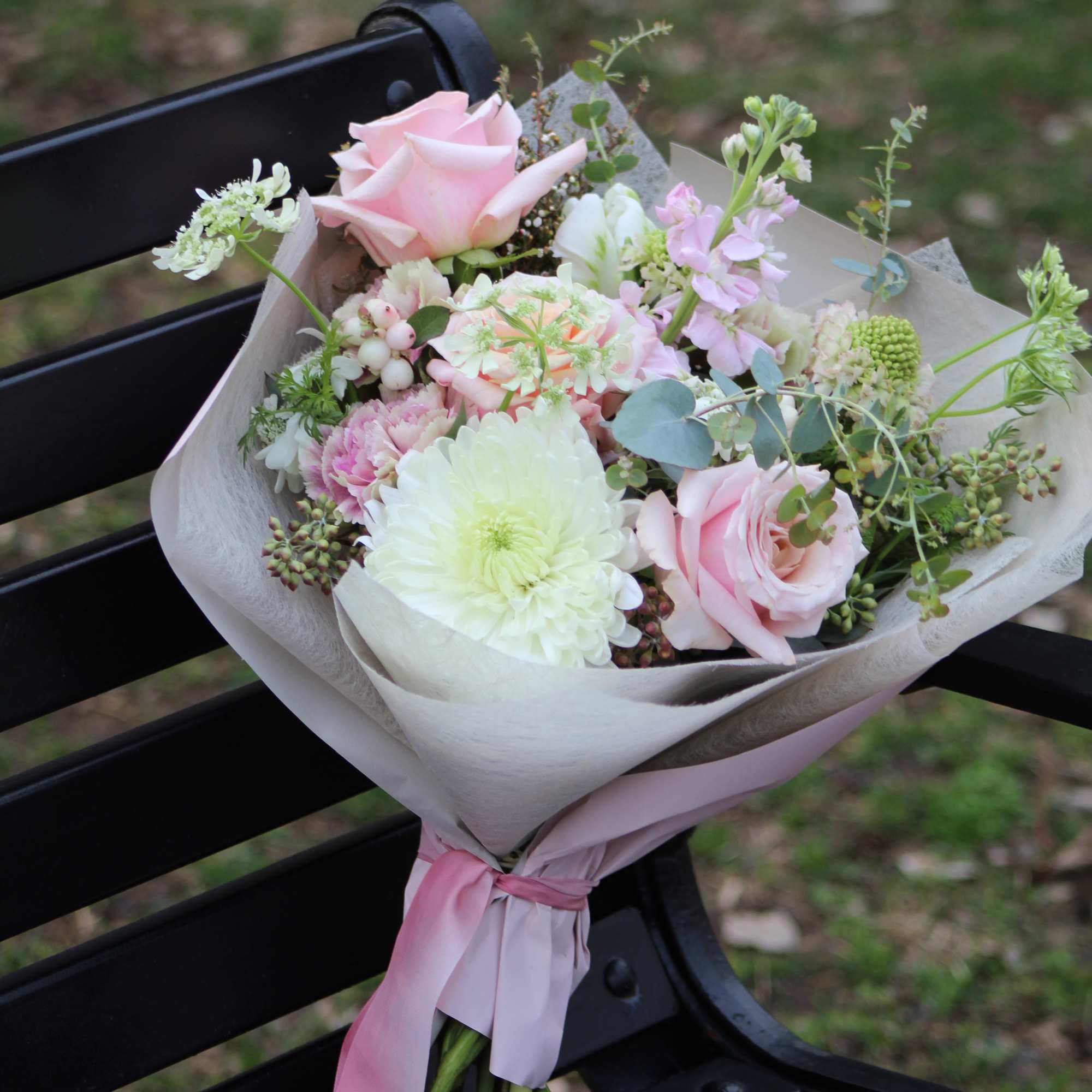 Pink and white bouquet with roses and mixed blooms wrapped in paper